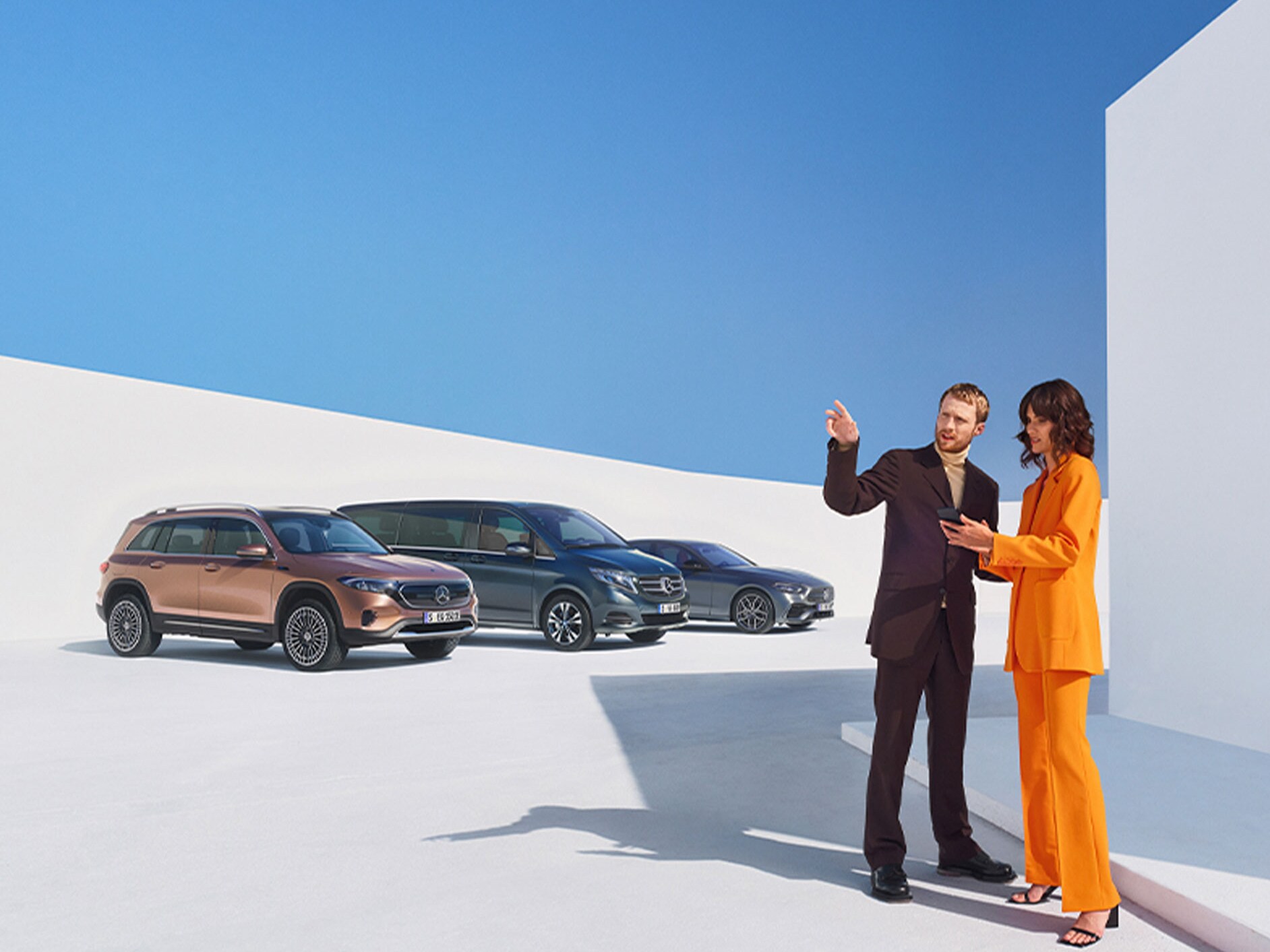 Un bărbat și o femeie în fața mai multor autovehicule Mercedes-Benz.