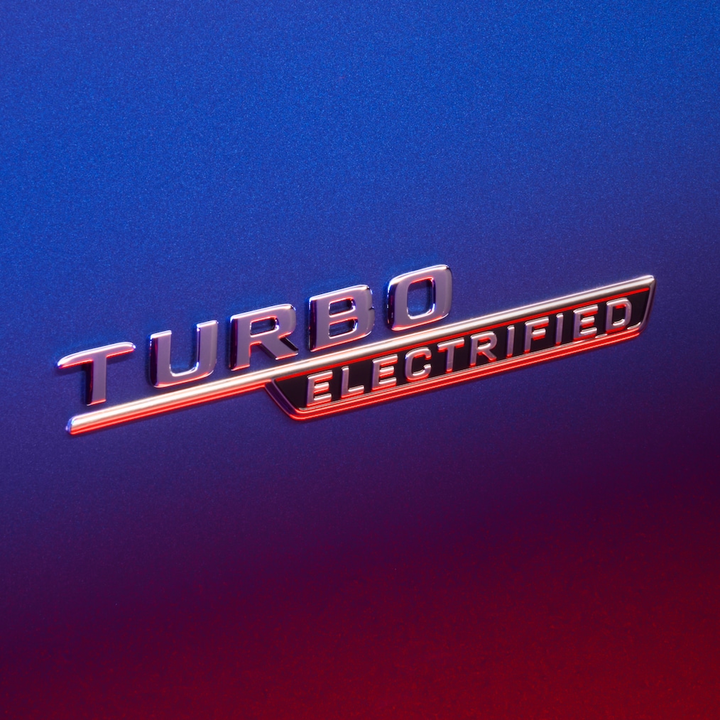 Inscripția TURBO E PERFORMANCE pe aripa față, iluminată de lumină roșie.