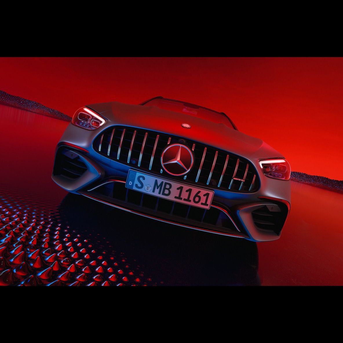 Modelul Mercedes-AMG C 63 S E PERFORMANCE dintr-o perspectivă frontală pe un fundal roșu.