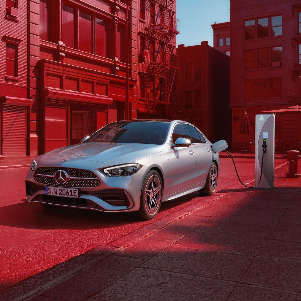 Perspectivă dinamică a unui model Mercedes-Benz Clasa C limuzină (instantaneu din timpul conducerii) sau staționând la o stație de încărcare.