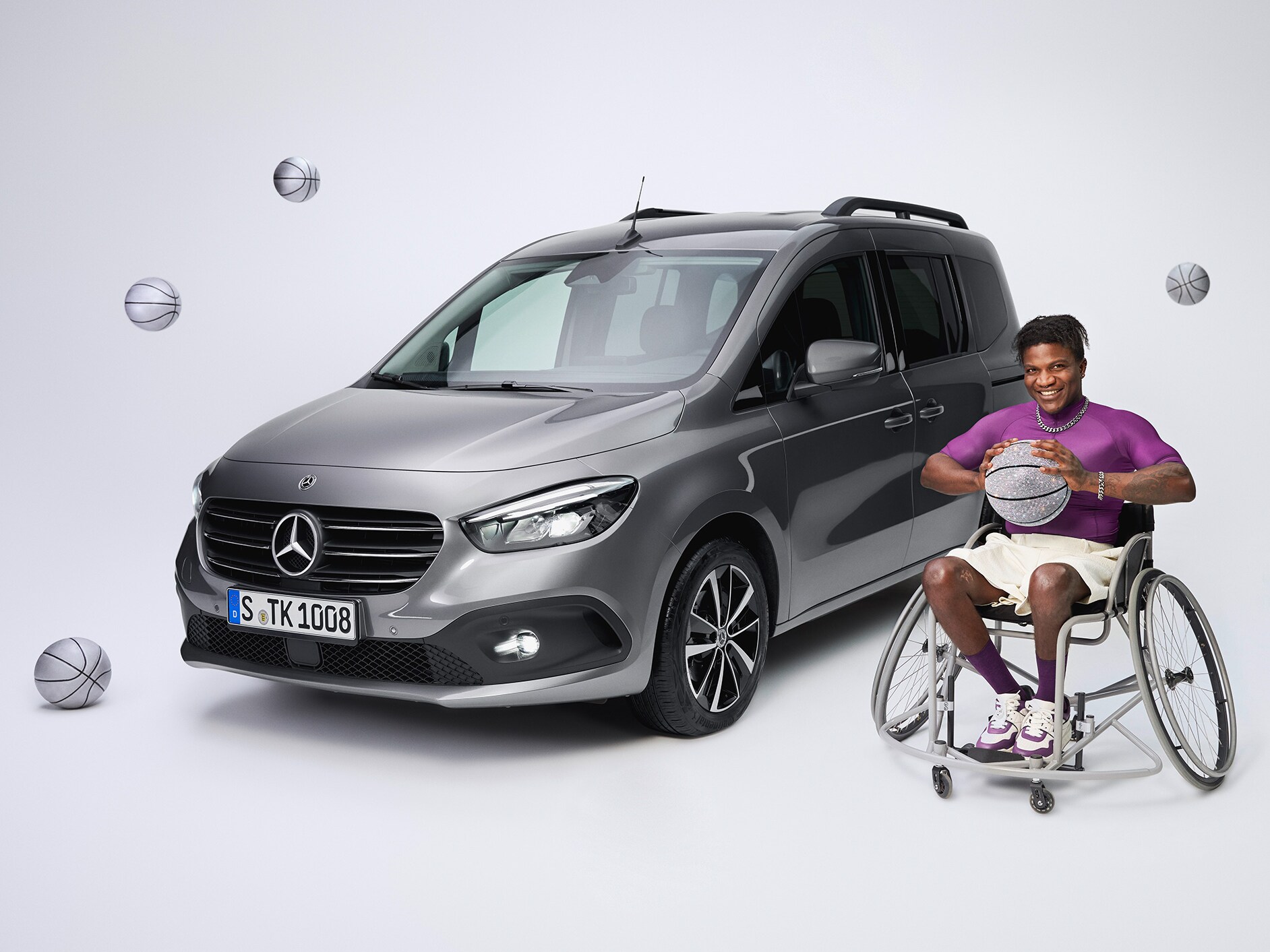 Modelul Mercedes-Benz Clasa T transformat pentru persoanele cu dizabilități, într-o vedere frontală oblică și un jucător de baschet în scaun cu rotile în prim-plan stânga.