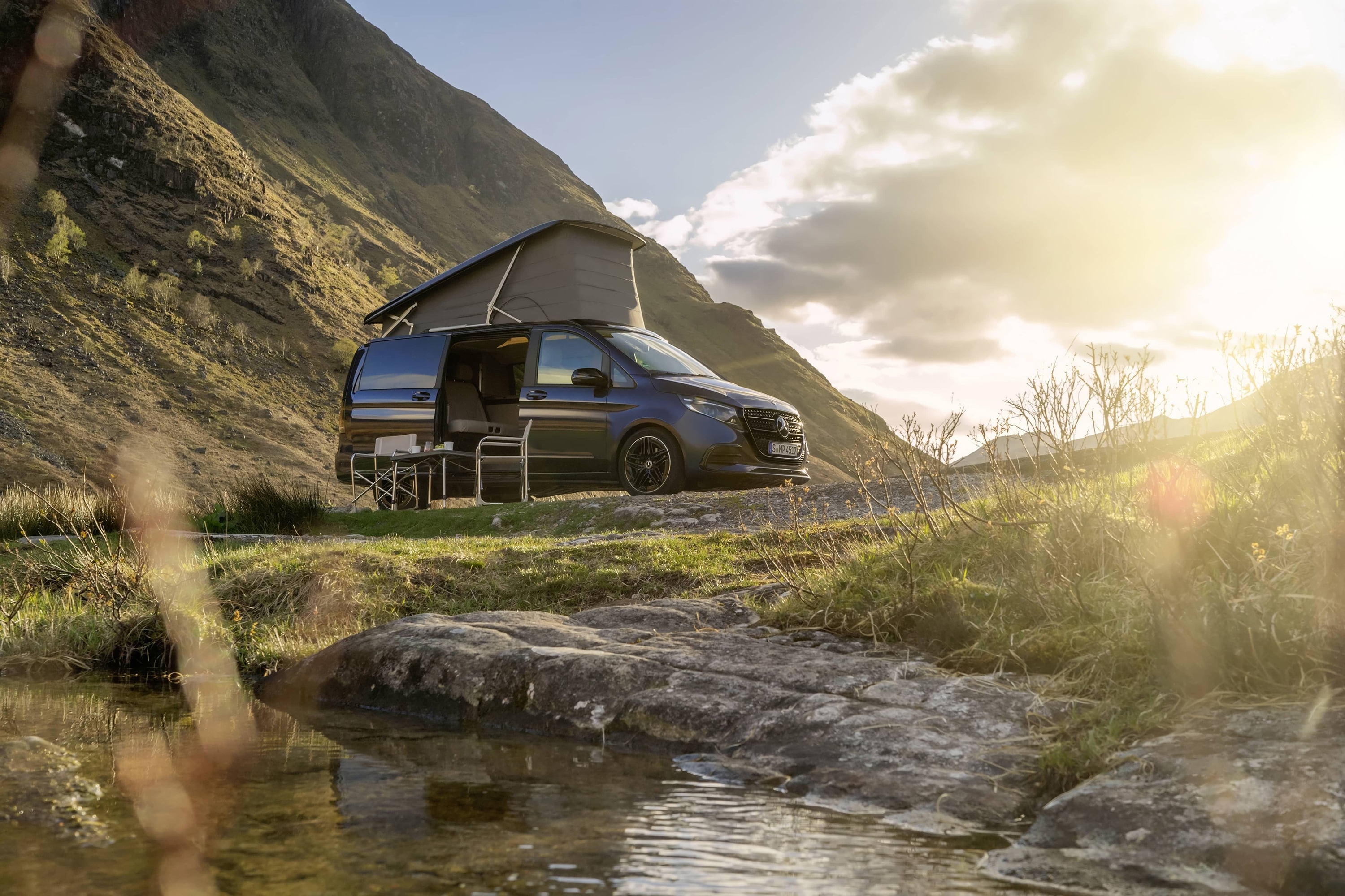 Marco Polo | Autorulote Sprinter | Mercedes-Benz Autorulotă Mercedes-Benz Marco Polo cu plafon mobil, într-un montan pitoresc, exprimând aventura în aer liber și libertatea oferită de viața la rulotă.
