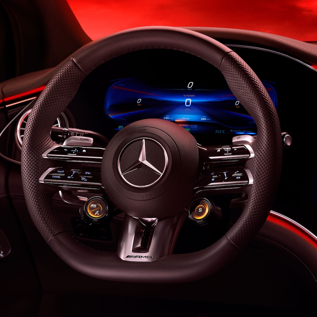 Imagine a volanului AMG Performance, văzut din scaunul șoferului, pe fundal roșu.