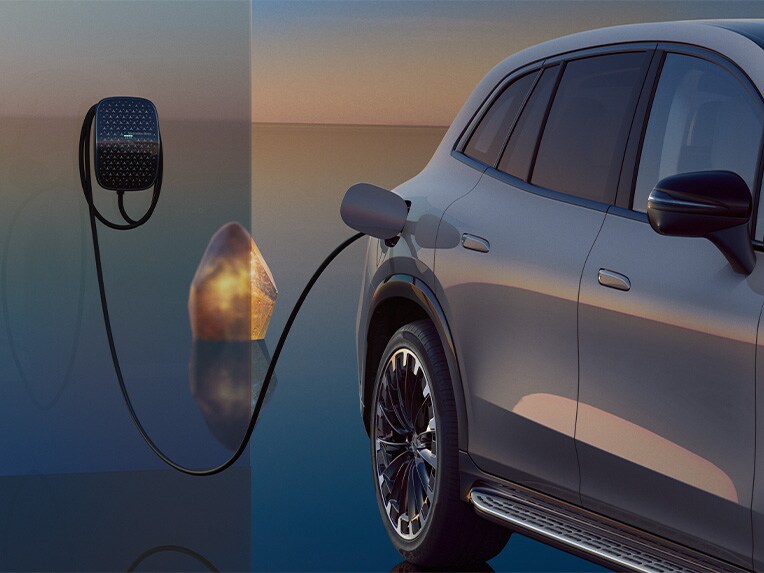 EQS SUV din perspectivă laterală în timpul unei proceduri de încărcare, conectat la o stație Mercedes-Benz Wallbox.