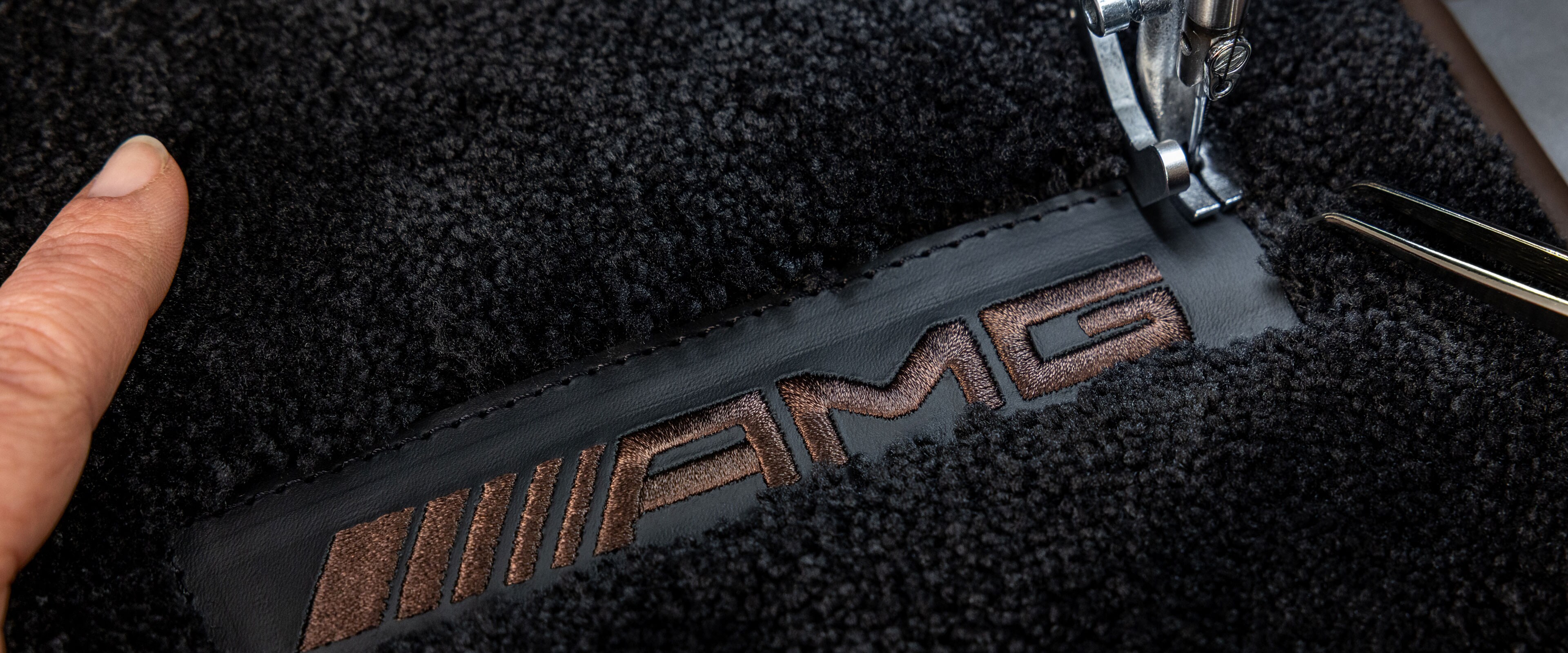 Inscripția MANUFAKTUR pe o suprafață întunecată într-un autovehicul Mercedes-AMG.