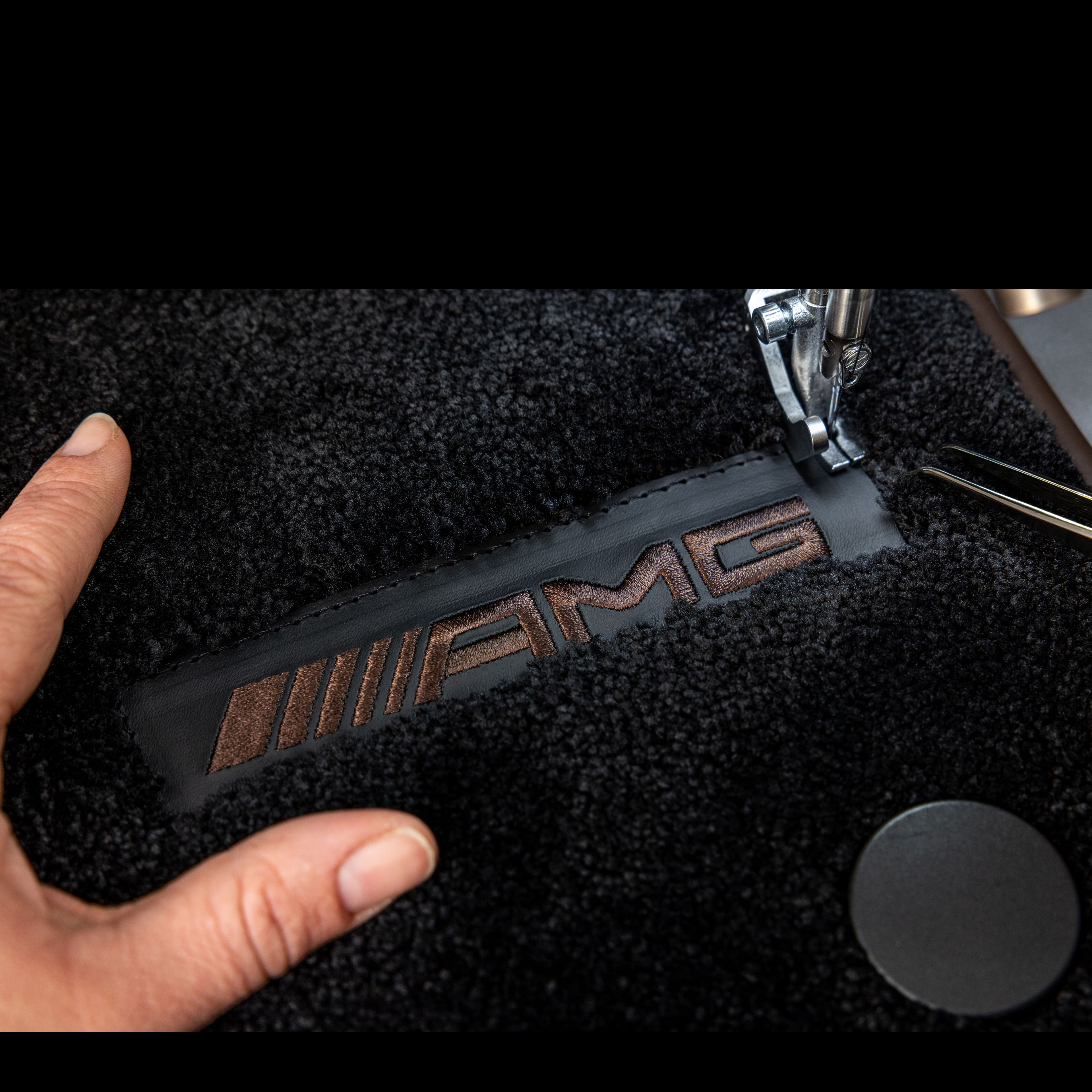 MANUFAKTUR | Mercedes-AMG Inscripția MANUFAKTUR pe o suprafață întunecată într-un autovehicul Mercedes-AMG.