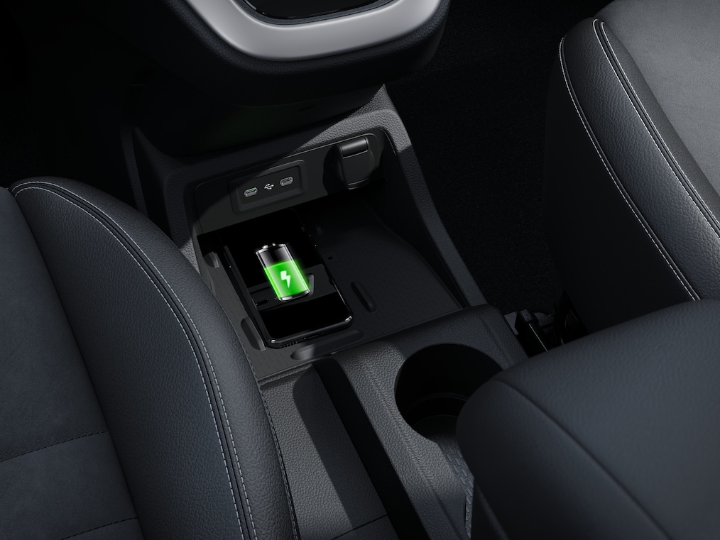 Imaginea prezintă consola centrală a autovehiculului, cu încărcătorul wireless în prim-plan. Un smartphone este așezat pe încărcător și se încarcă.