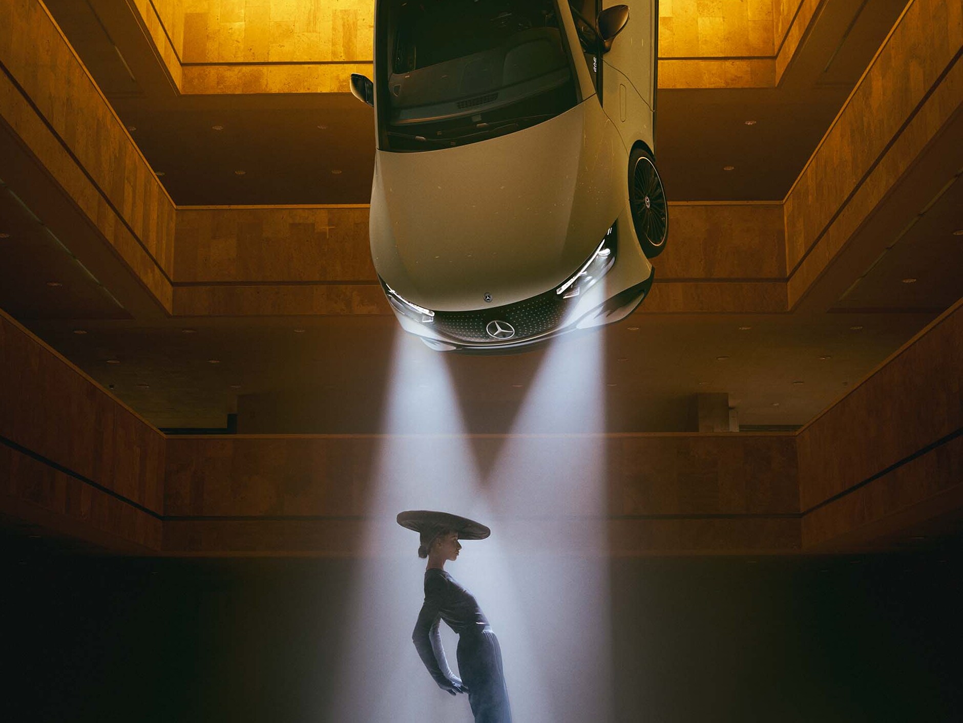 O încăpere întunecată, de al cărui plafon sunt suspendate faruri în al căror fascicul luminos se află o femeie.