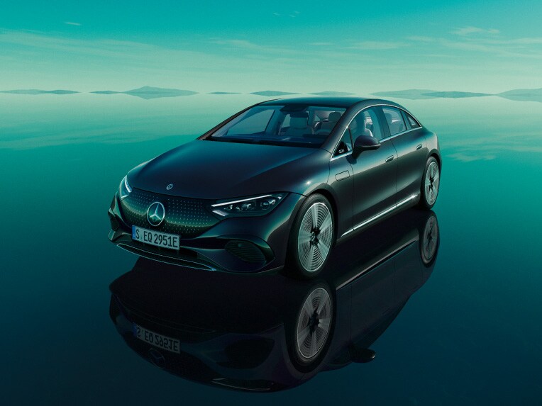 Modelul complet electric EQE de la Mercedes-Benz staționând în universul său verde, cu podea reflectantă.