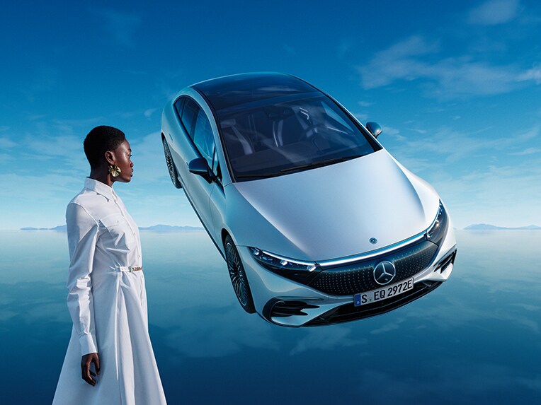 Modelul complet electric EQS de la Mercedes-Benz staționând în universul său albastru, cu podea reflectantă.