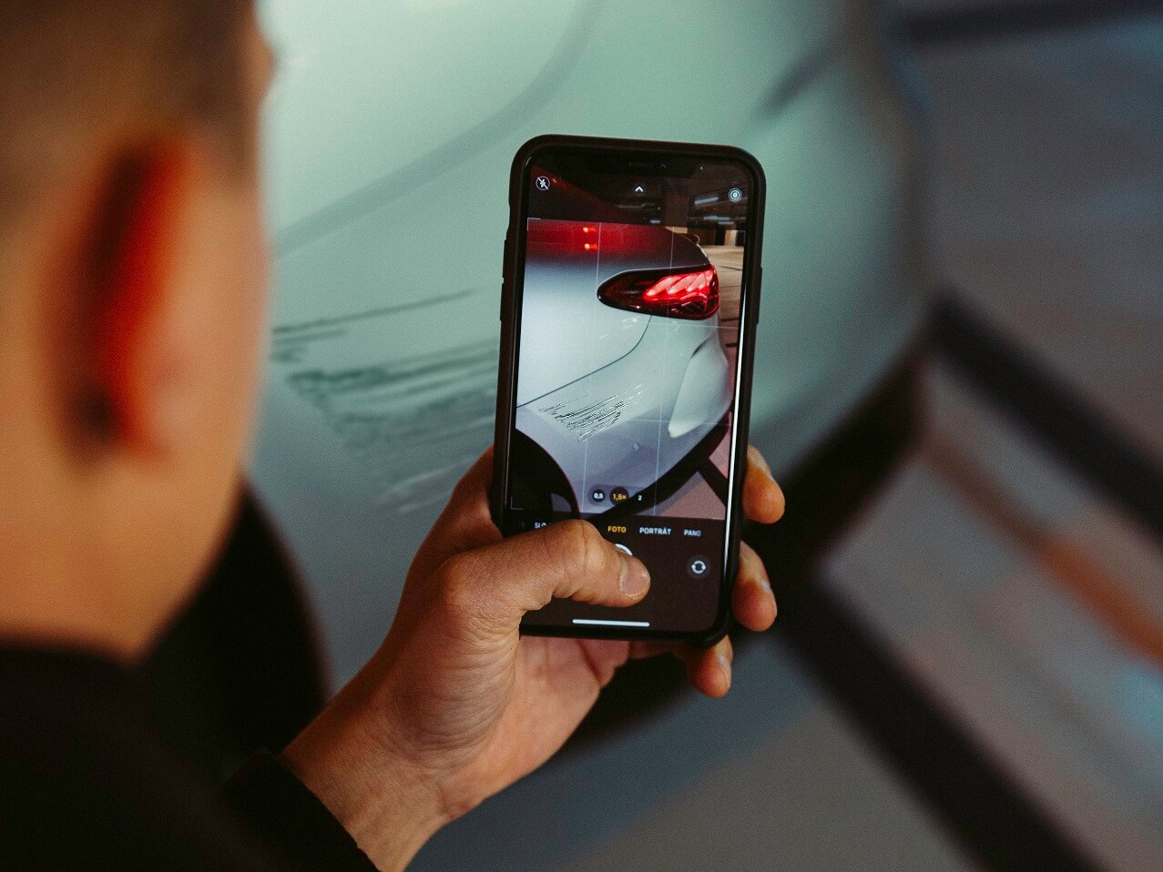 Un șofer documentează avariile la autovehicul cu smartphone-ul său.