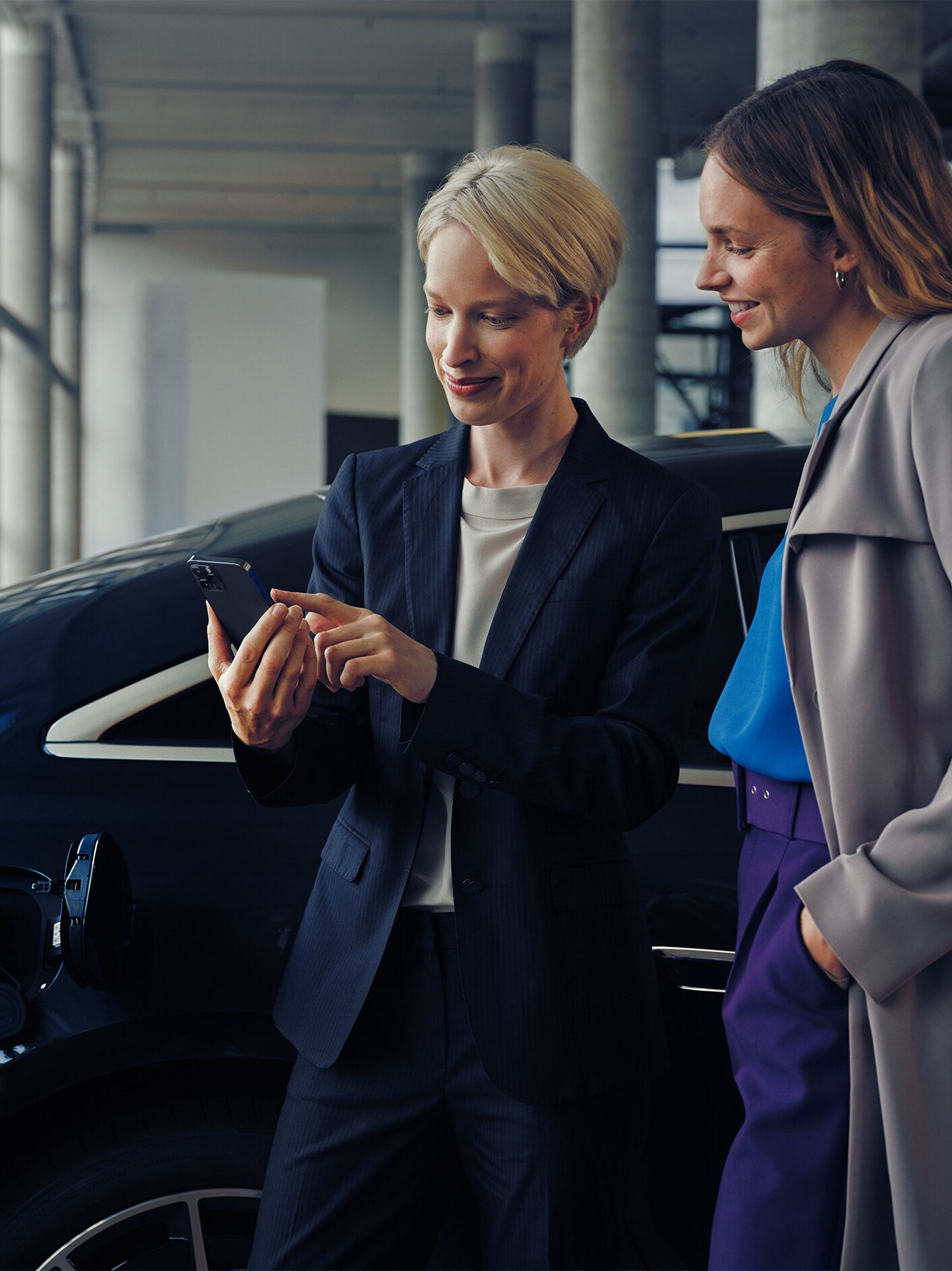 Două femei în fața unui model EQE limuzină care se încarcă.