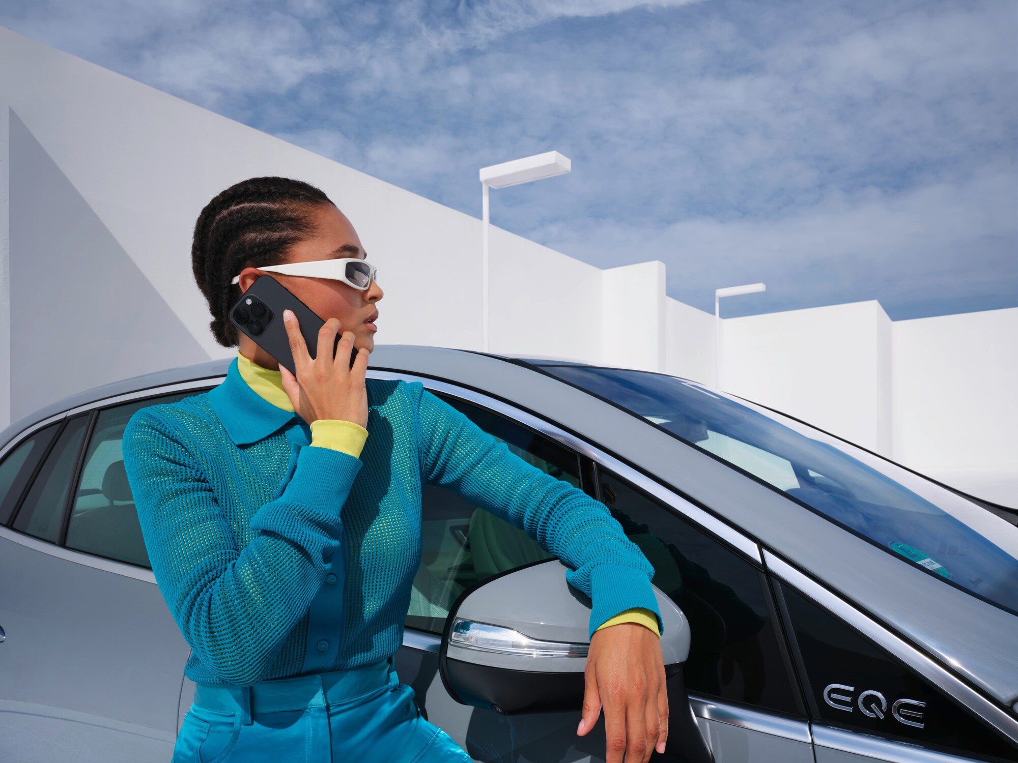 O persoană sprijinită de un autovehicul Mercedes-Benz cu telefonul în mână.