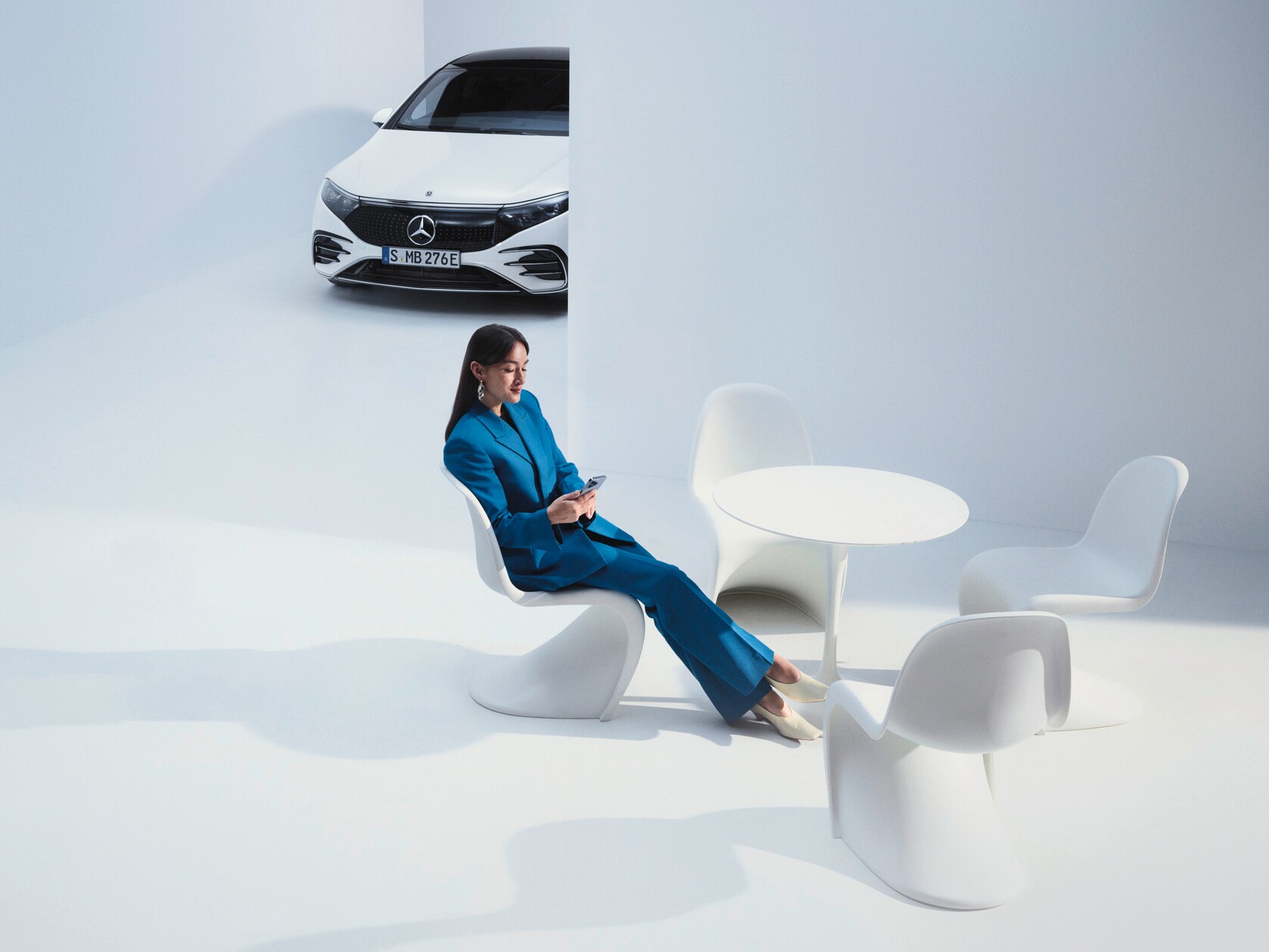 Femeie într-o convorbire telefonică în fața autovehiculului său Mercedes