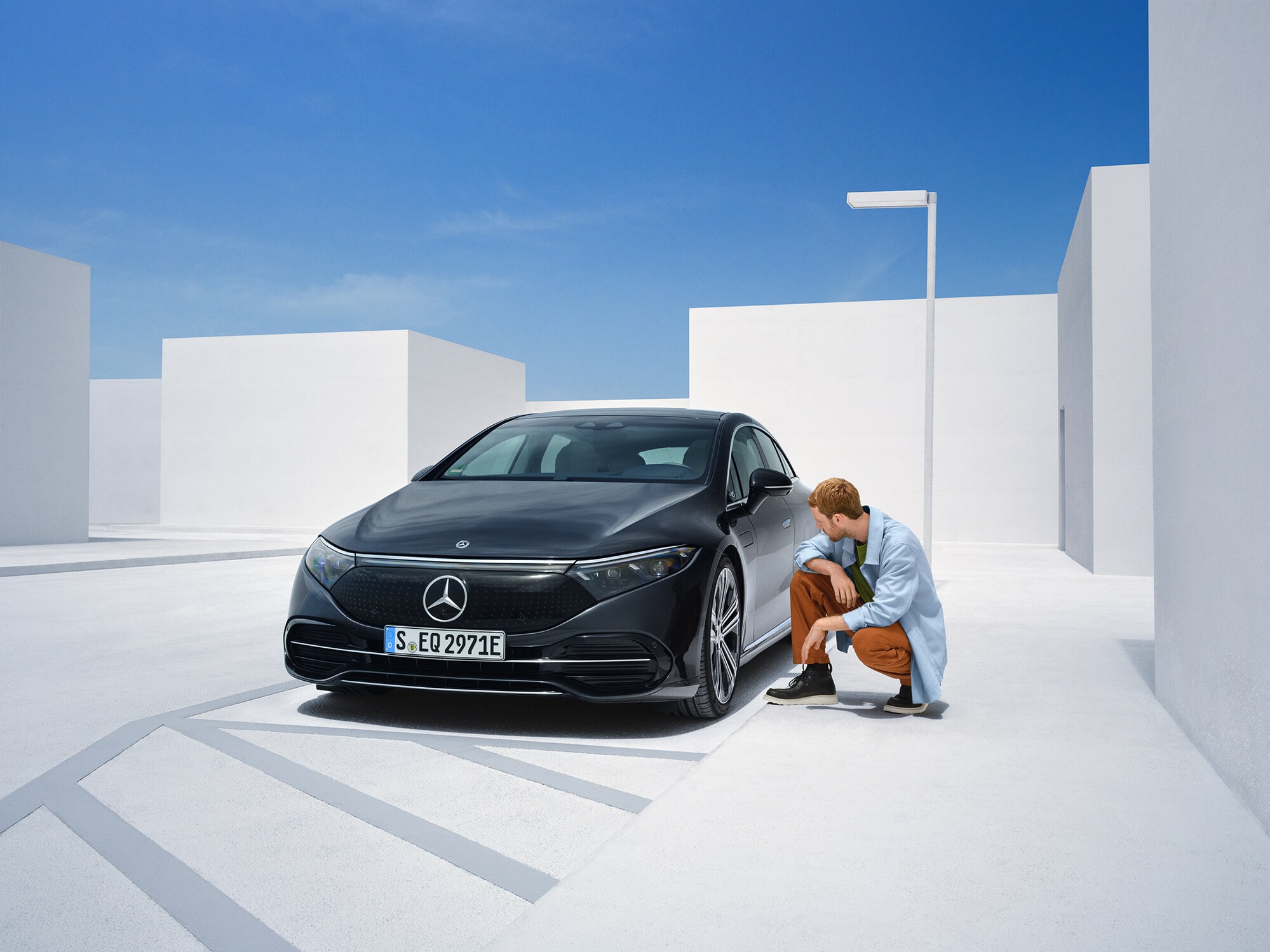 O persoană se apleacă lângă autovehiculul său Mercedes-Benz pentru a-l verifica.