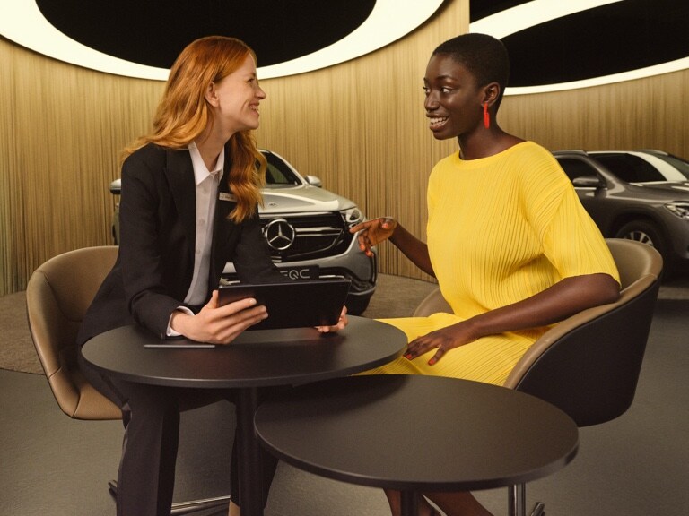 Două femei se informează pe o tabletă despre Aplicațiile Mercedes me și extraopțiunile digitale.