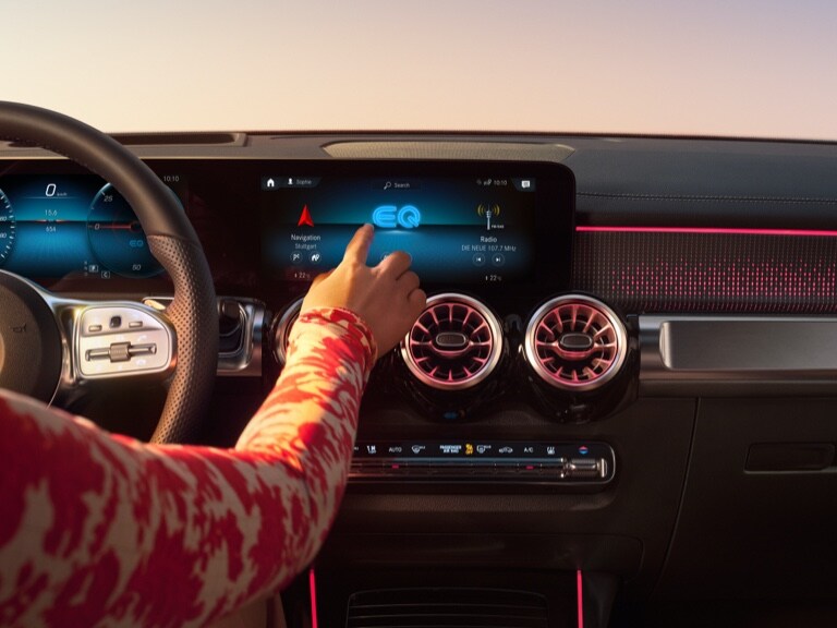 O femeie pornește navigația pe sistemul Multimedia MBUX de la Mercedes-Benz.