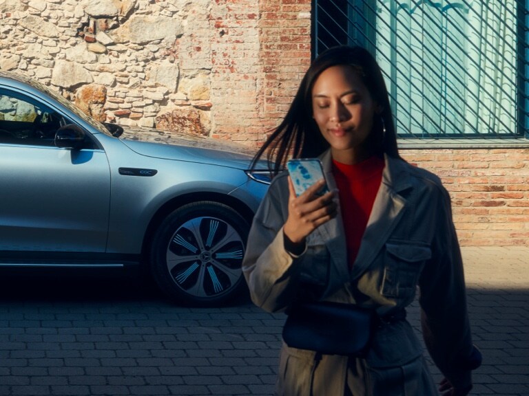 O femeie utilizează Aplicația Mercedes me de pe smartphone-ul său pentru a se conecta cu autovehiculul său Mercedes-Benz.
