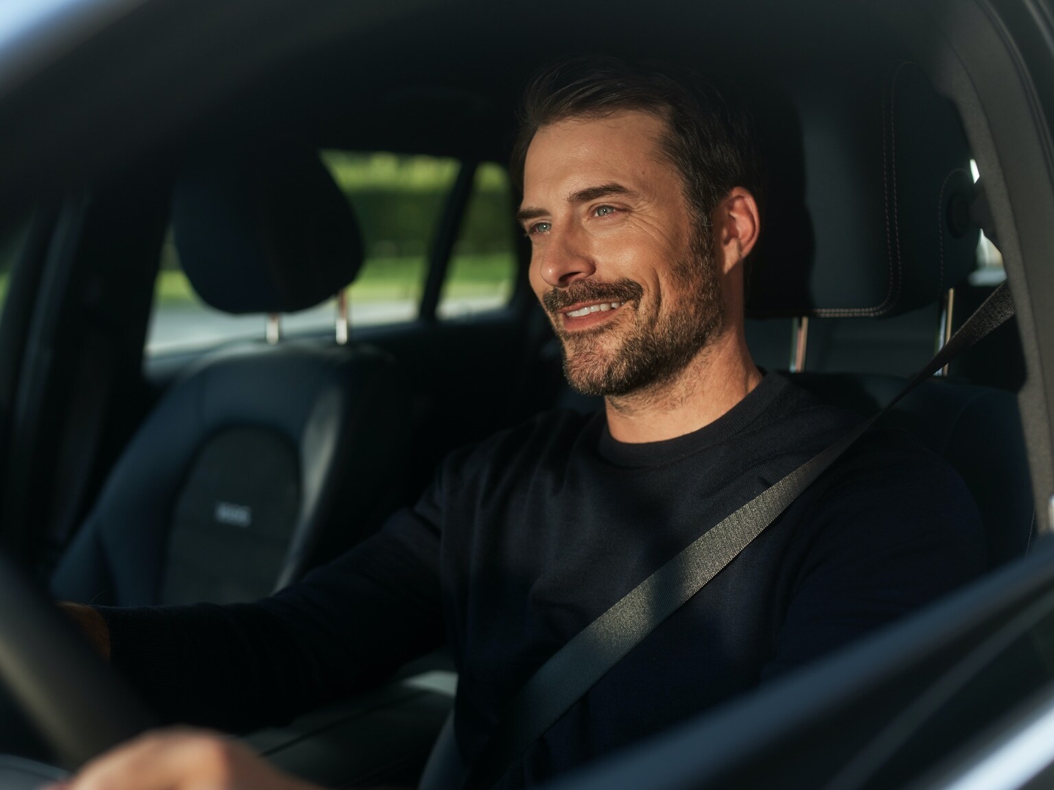 Un bărbat se bucură de radio prin internet, fără întreruperi, în autovehiculul său Mercedes-Benz, datorită pachetului Entertainment.