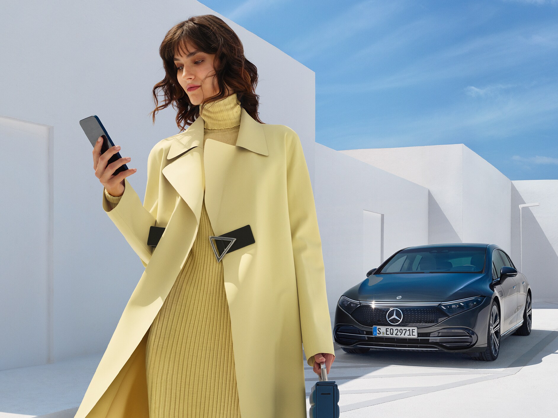 O femeie stând în fața unei limuzine EQS de la Mercedes-Benz.