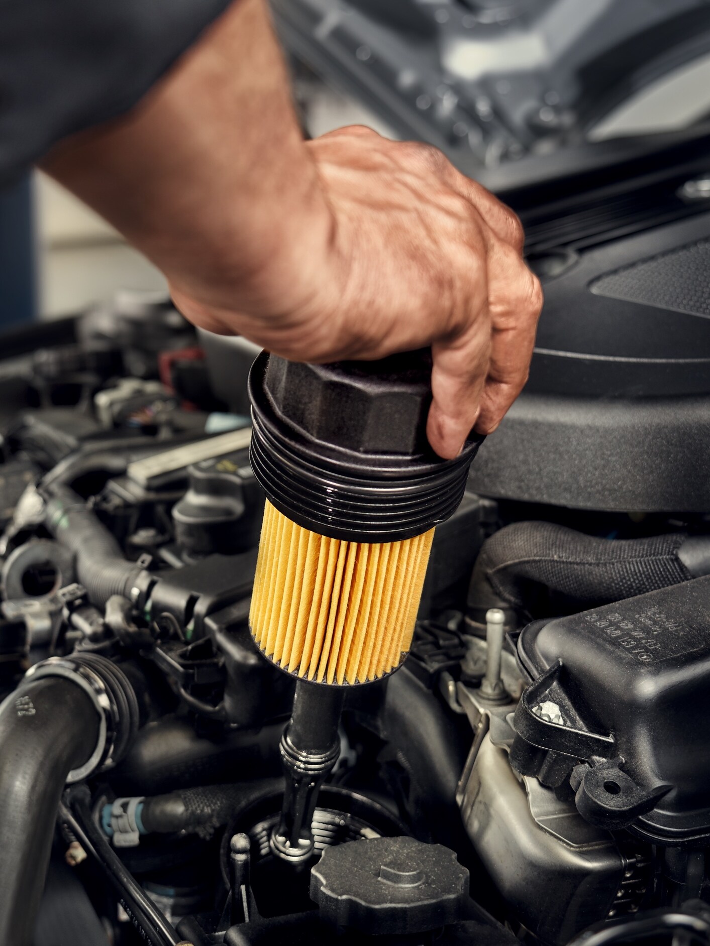 Un tehnician care instalează filtrul de ulei pe un autovehicul Mercedes-Benz.