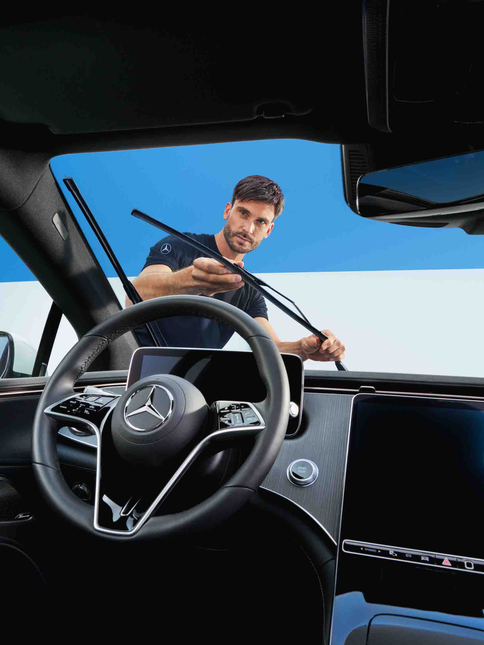 O persoană care reglează ștergătoarele de parbriz ale unui autovehicul Mercedes-Benz.