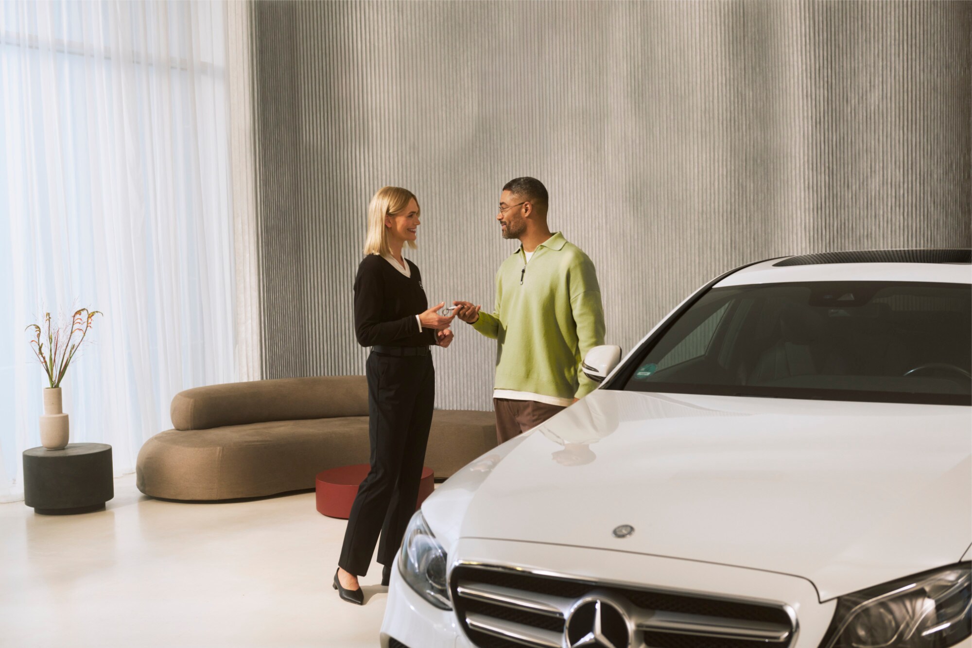 Un consultant Mercedes-Benz care predă cheile unui autovehicul unui client.
