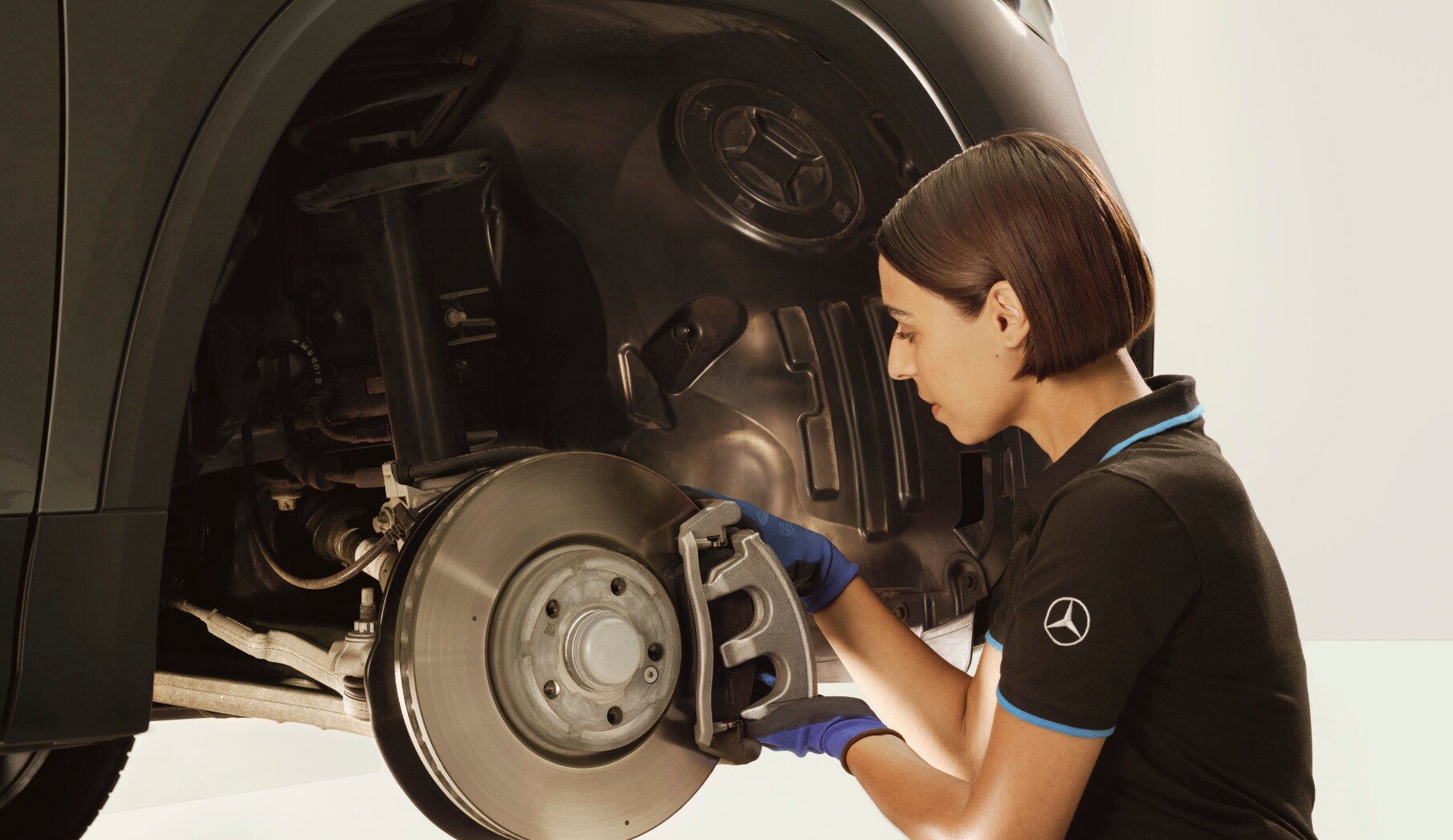 Un tehnician repară frânele unui autovehicul Mercedes-Benz.