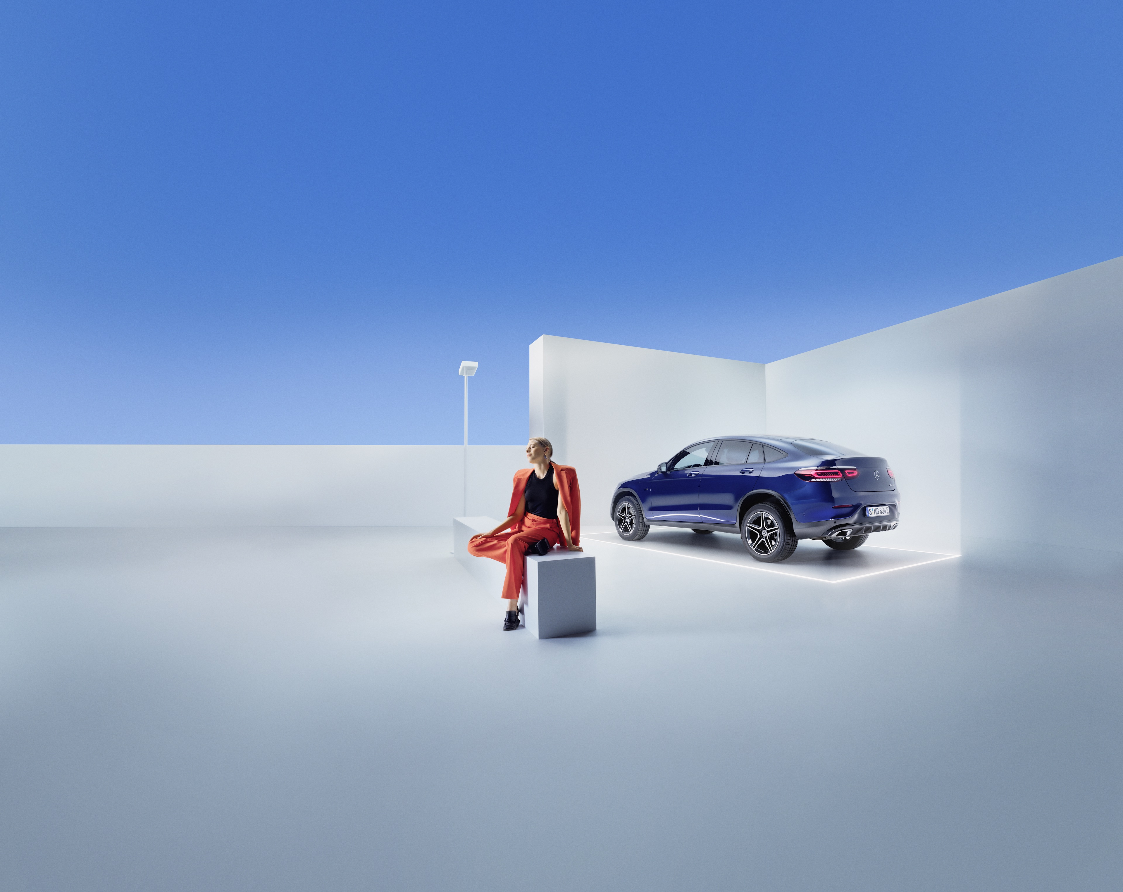 Contracte de service | Mercedes-Benz O femeie stă pe o bancă în fața unui Mercedes-Benz.