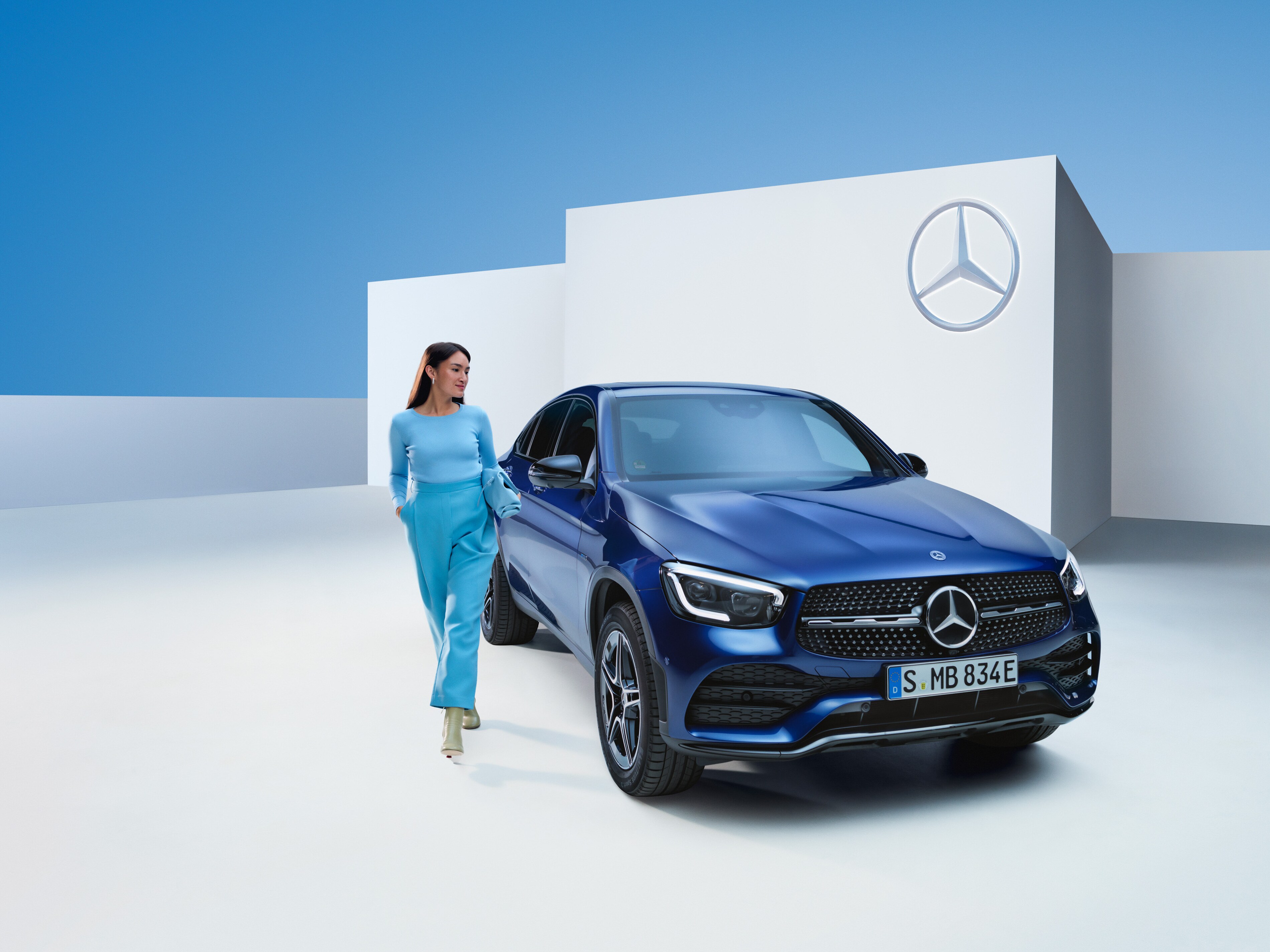 O femeie merge pe lângă autovehiculul său Mercedes-Benz.