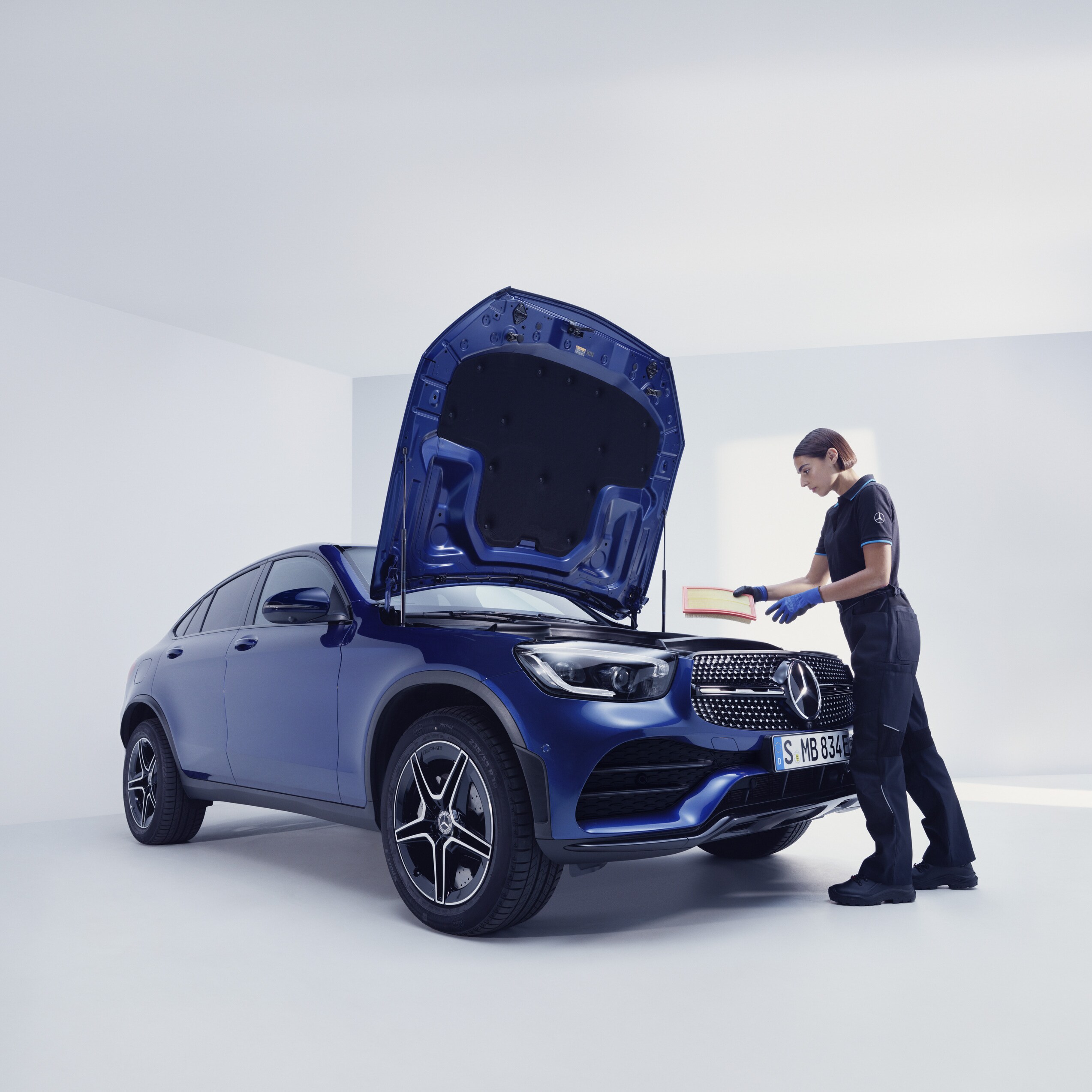 Un mecanic de la Mercedes-Benz examinează un Mercedes-Benz.