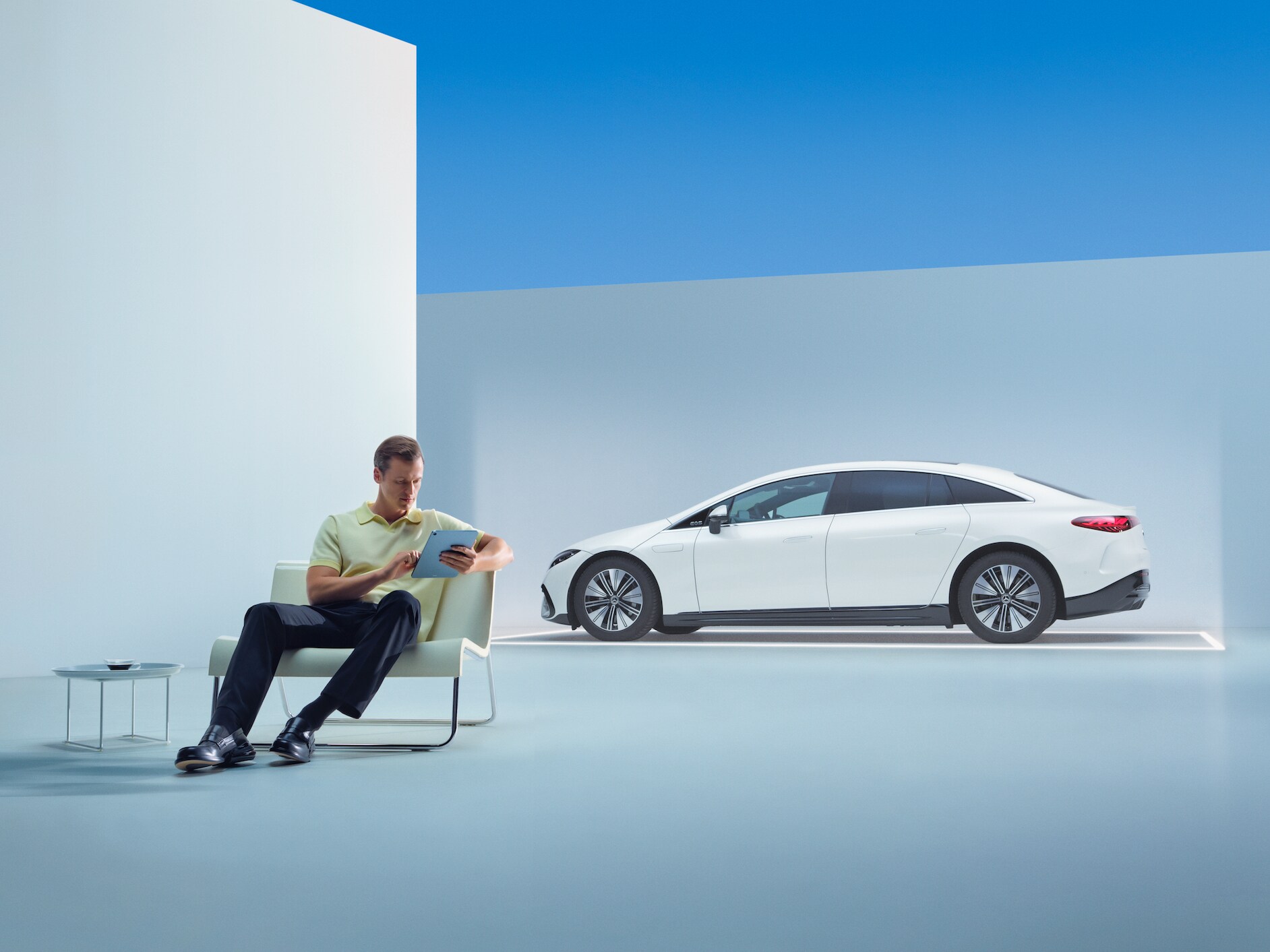 O persoană folosind o tabletă stă în fața unui autovehicul Mercedes-Benz.