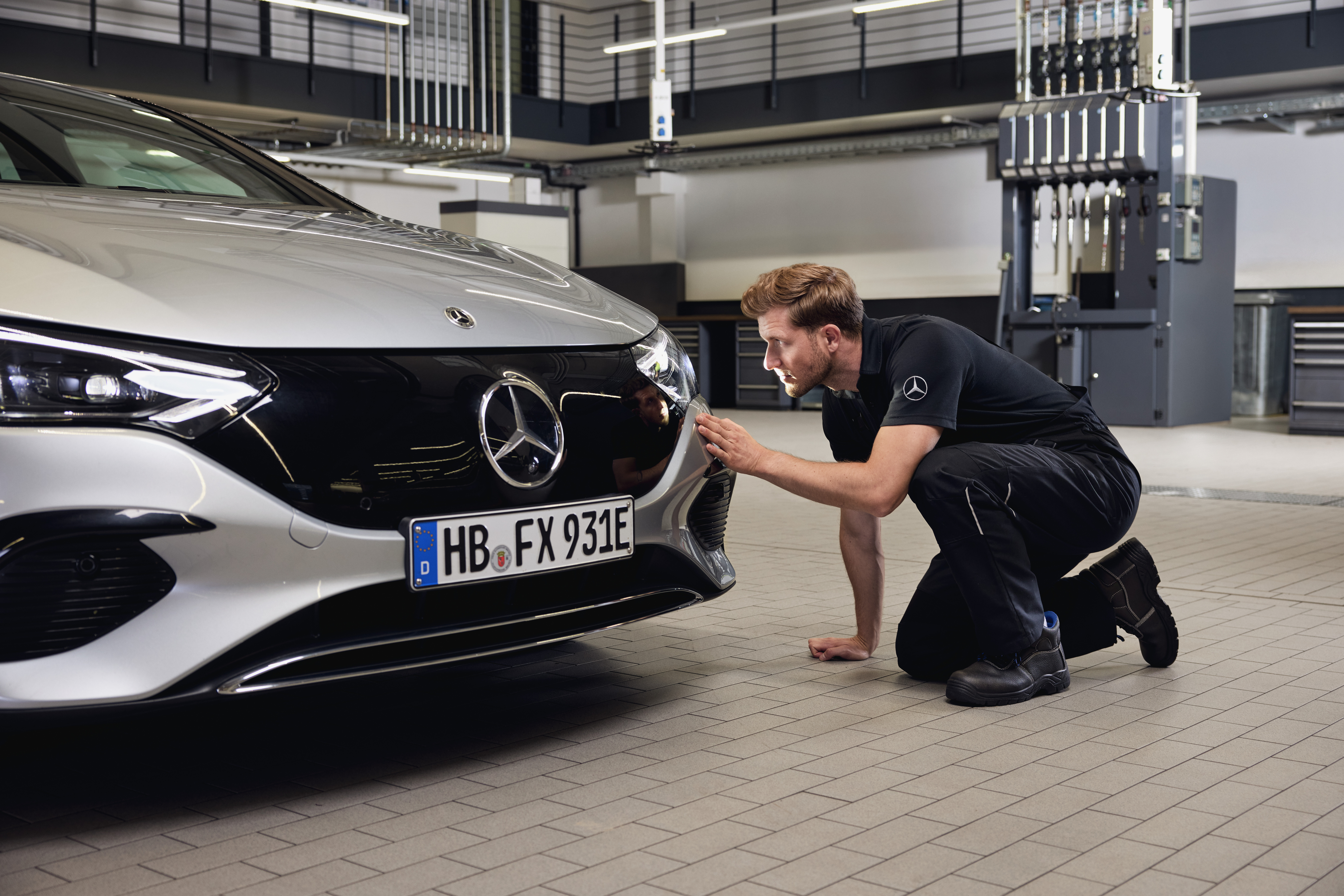 Înlocuire de faruri de origine Mercedes-Benz Prim-plan al părții din față a autovehiculului Mercedes‑Benz cu un tehnician care efectuează o examinare detaliată.