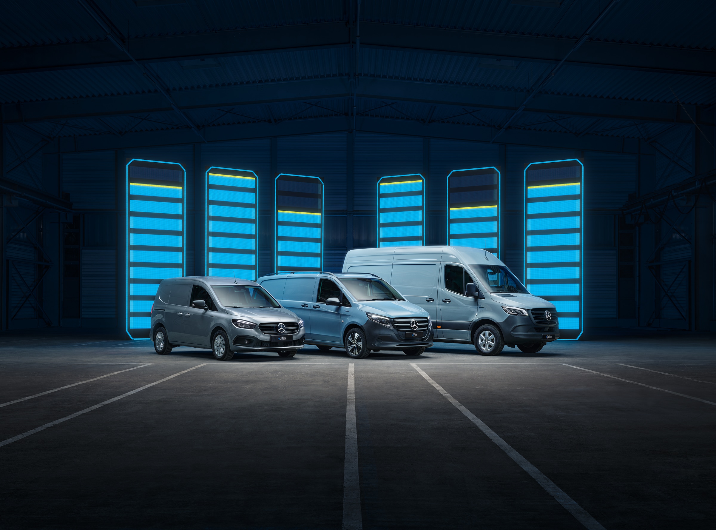Gama de autovehicule comerciale electrice Mercedes-Benz | Istoria autovehiculelor utilitare | Mercedes-Benz Gama de autovehicule comerciale electrice Mercedes-Benz prezentate într-un depozit futurist, cu bare de încărcare iluminate