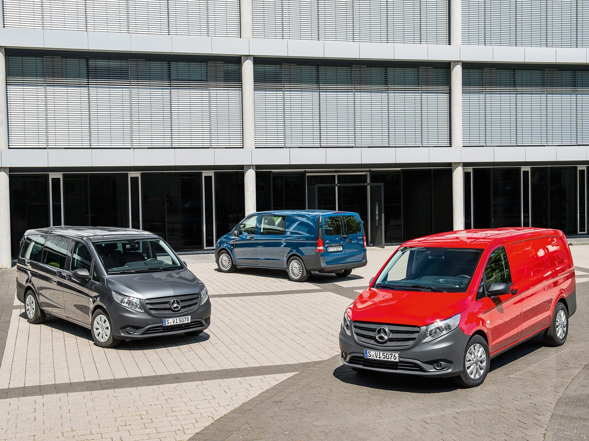 Mai multe modele Mercedes-Benz Vito parcate în fața unei clădiri moderne de birouri