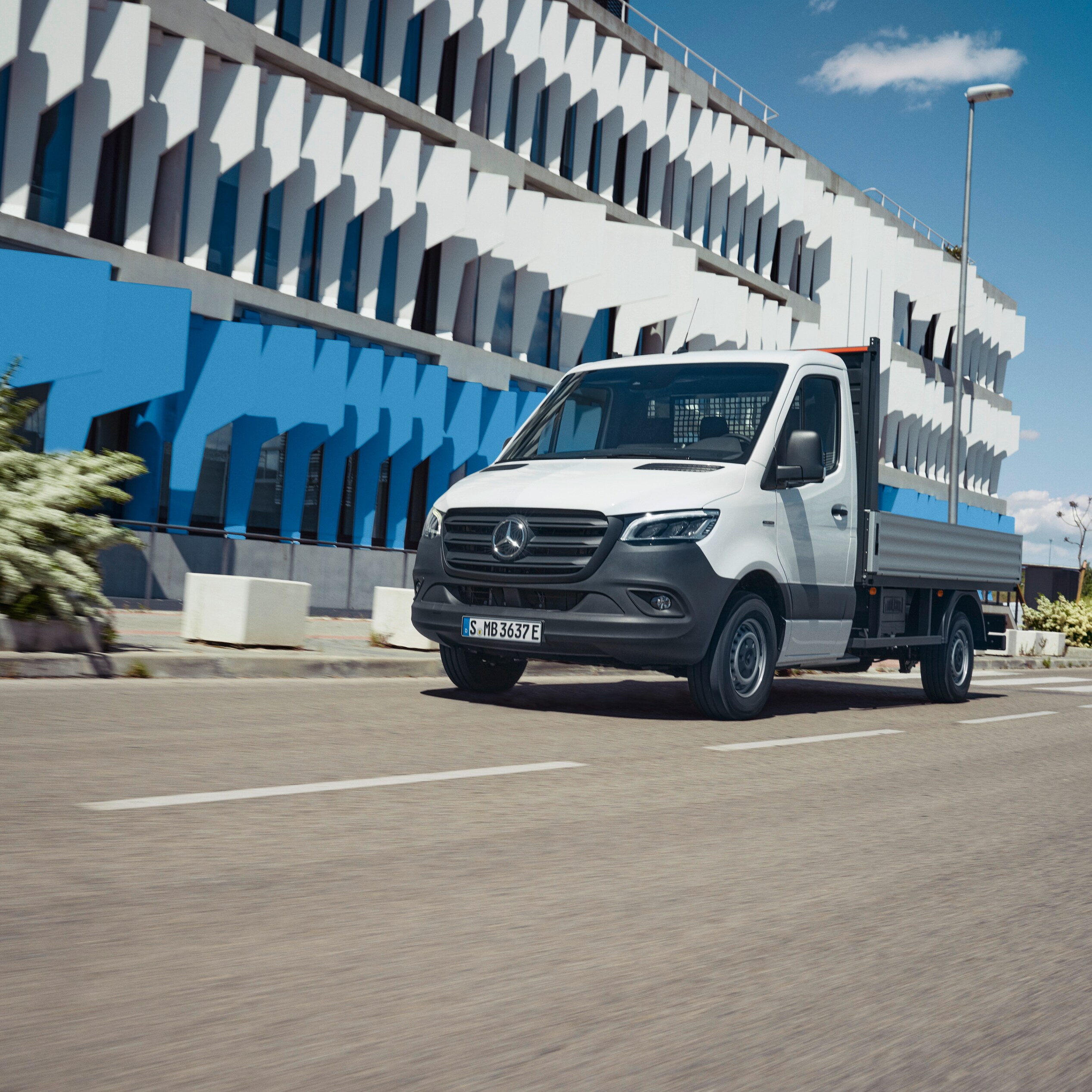 Autovehiculul cu platformă Mercedes-Benz eSprinter pe drum, în oraș.