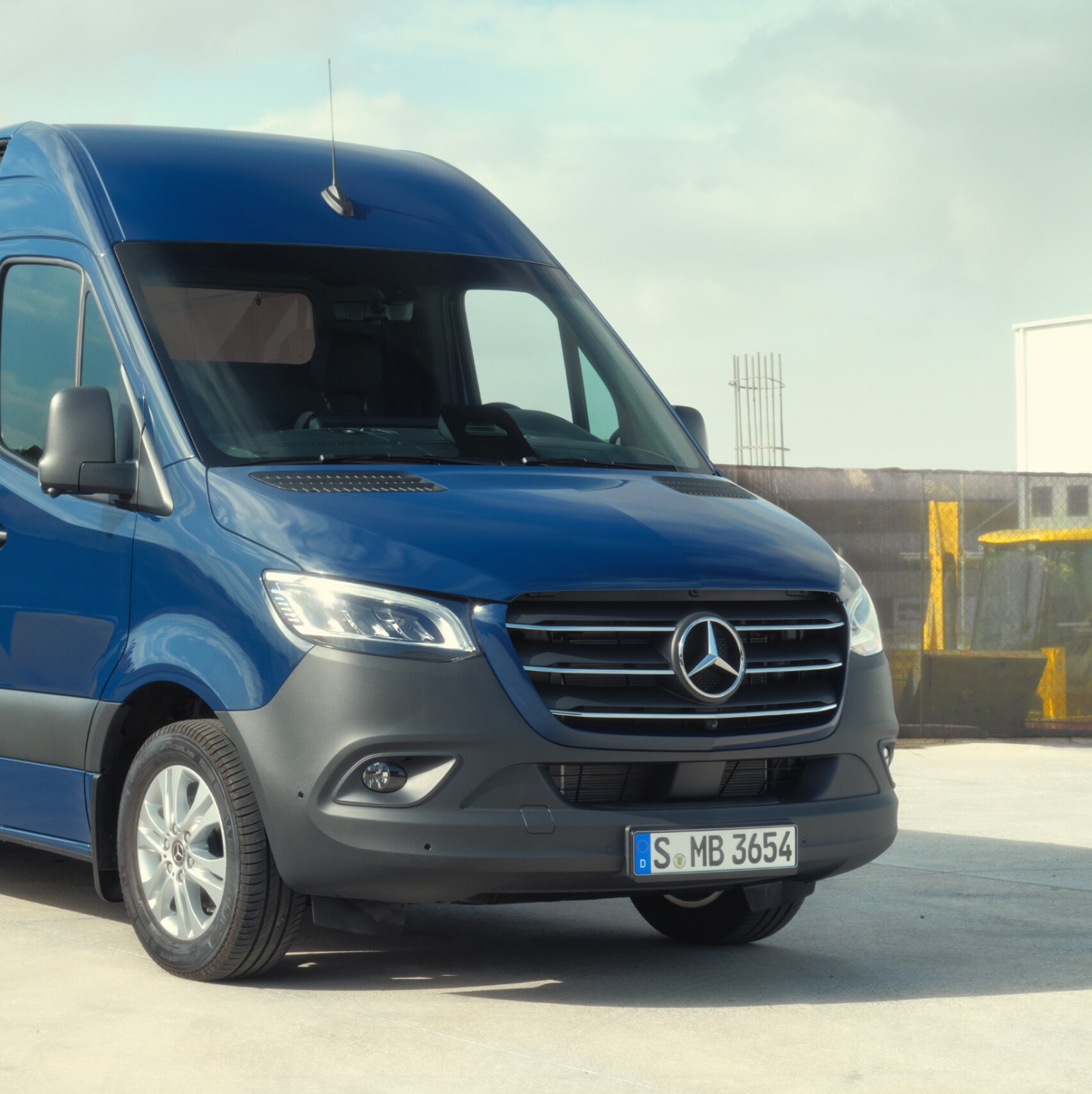 Modelul Mercedes-Benz Sprinter furgonetă cu panou în fața unor materiale de construcții.