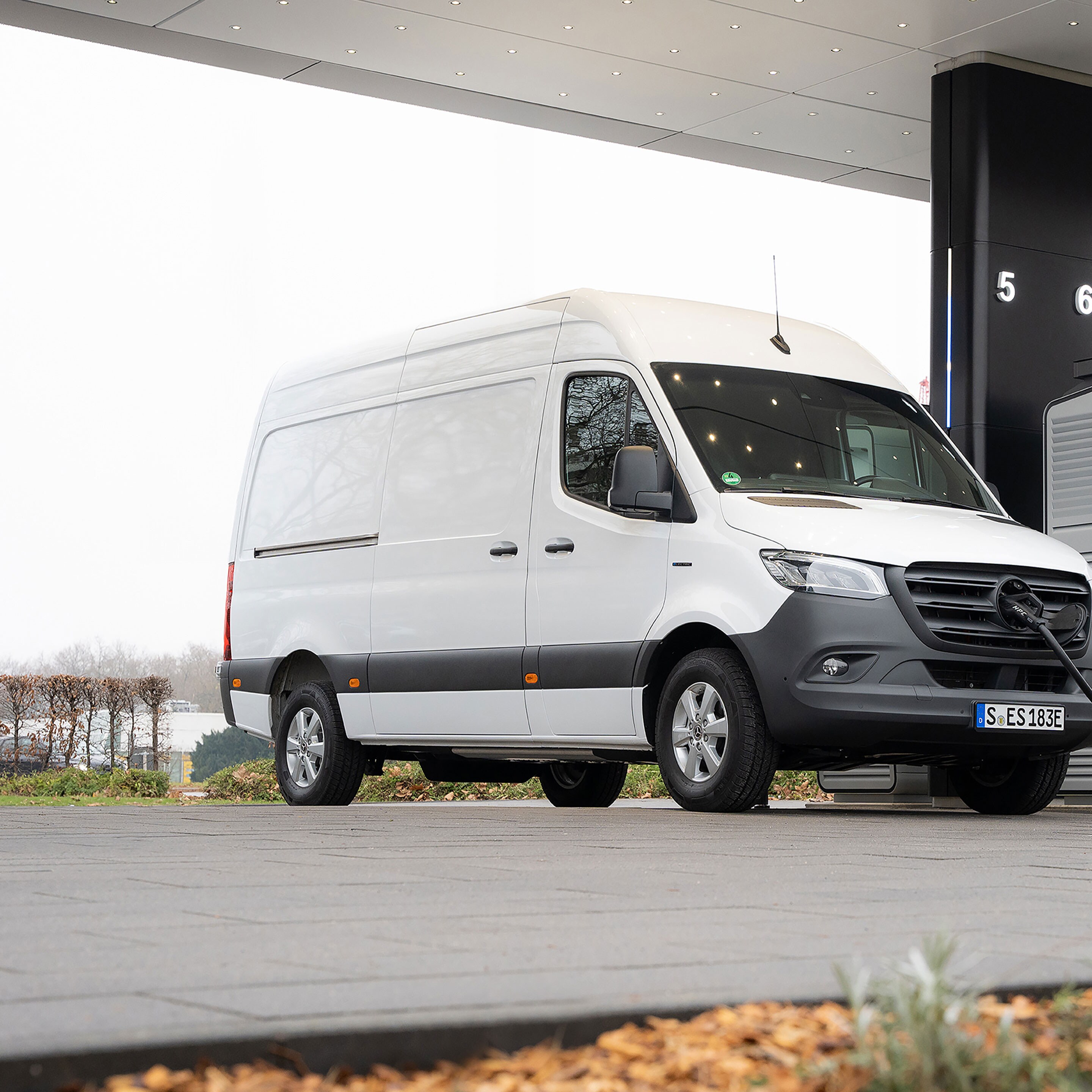 O furgonetă Mercedes-Benz în fața unei stații de încărcare, în timp ce se încarcă.