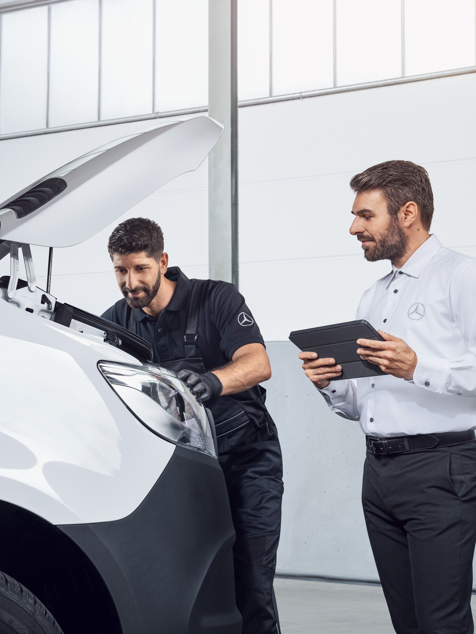 Doi bărbați testează un model Mercedes Sprinter cu tableta și capota motorului deschisă, subiect: Piese de schimb  de origineMercedes-Benz Sprinter.