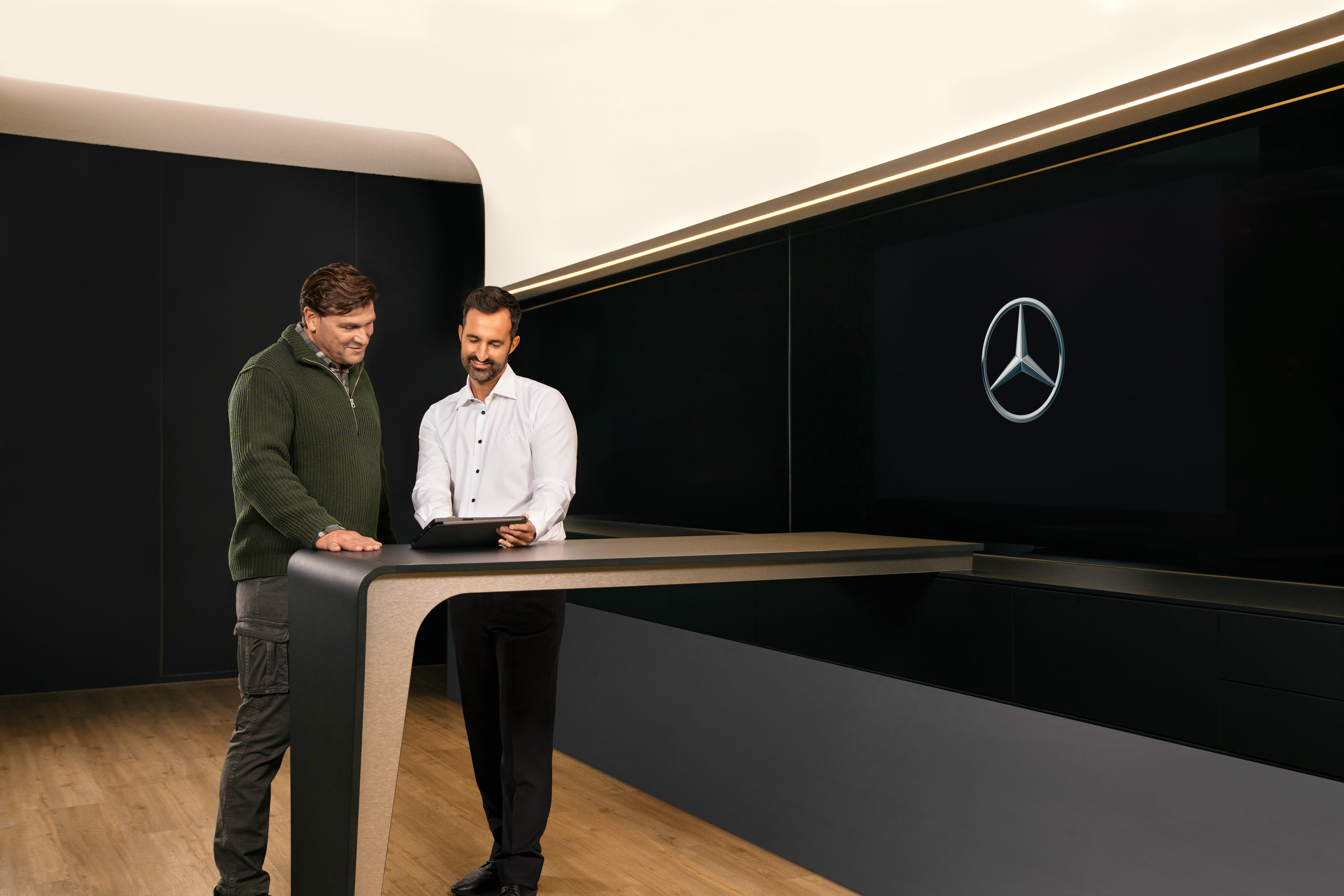 Mercedes-Benz | ServiceCare pentru furgonete Doi bărbați se consultă în jurul unei mese și se uită la un iPad.