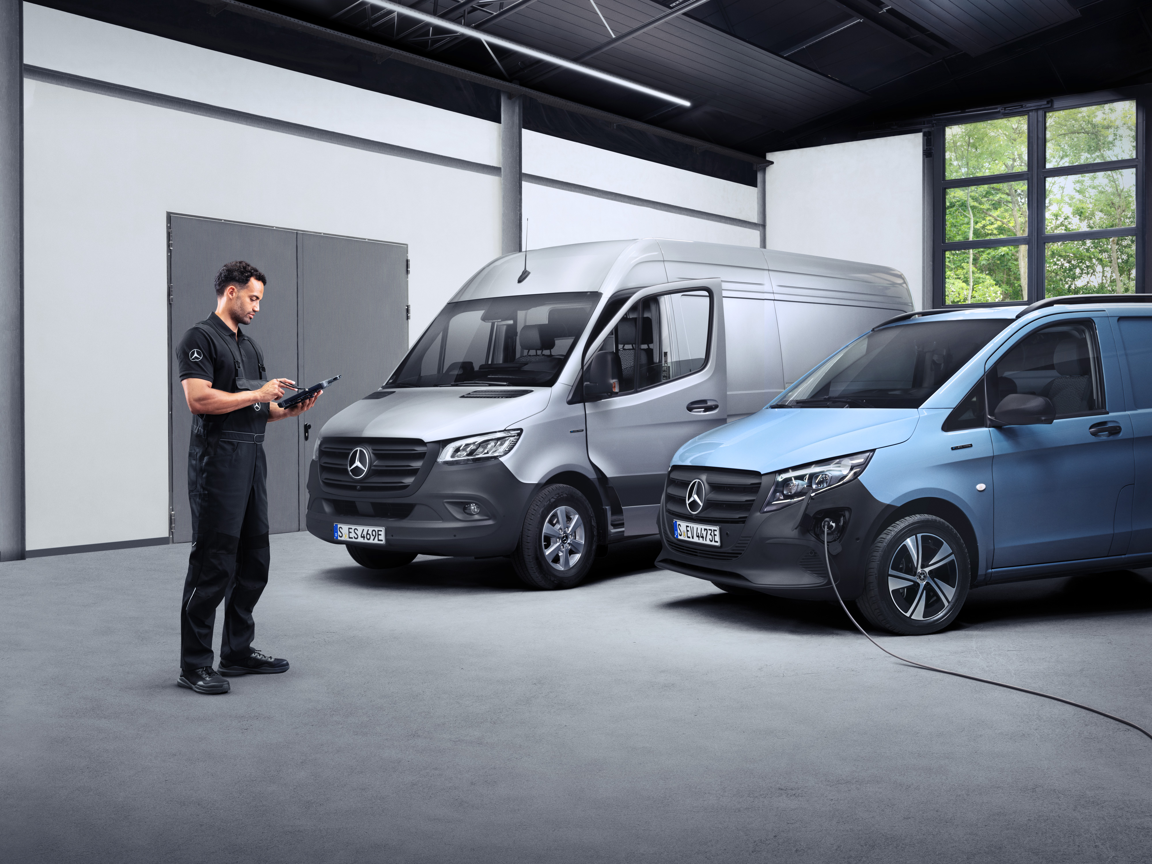 Mercedes-Benz | ServiceCare pentru furgonete Un tehnician cu o tabletă în fața a două furgonete electrice