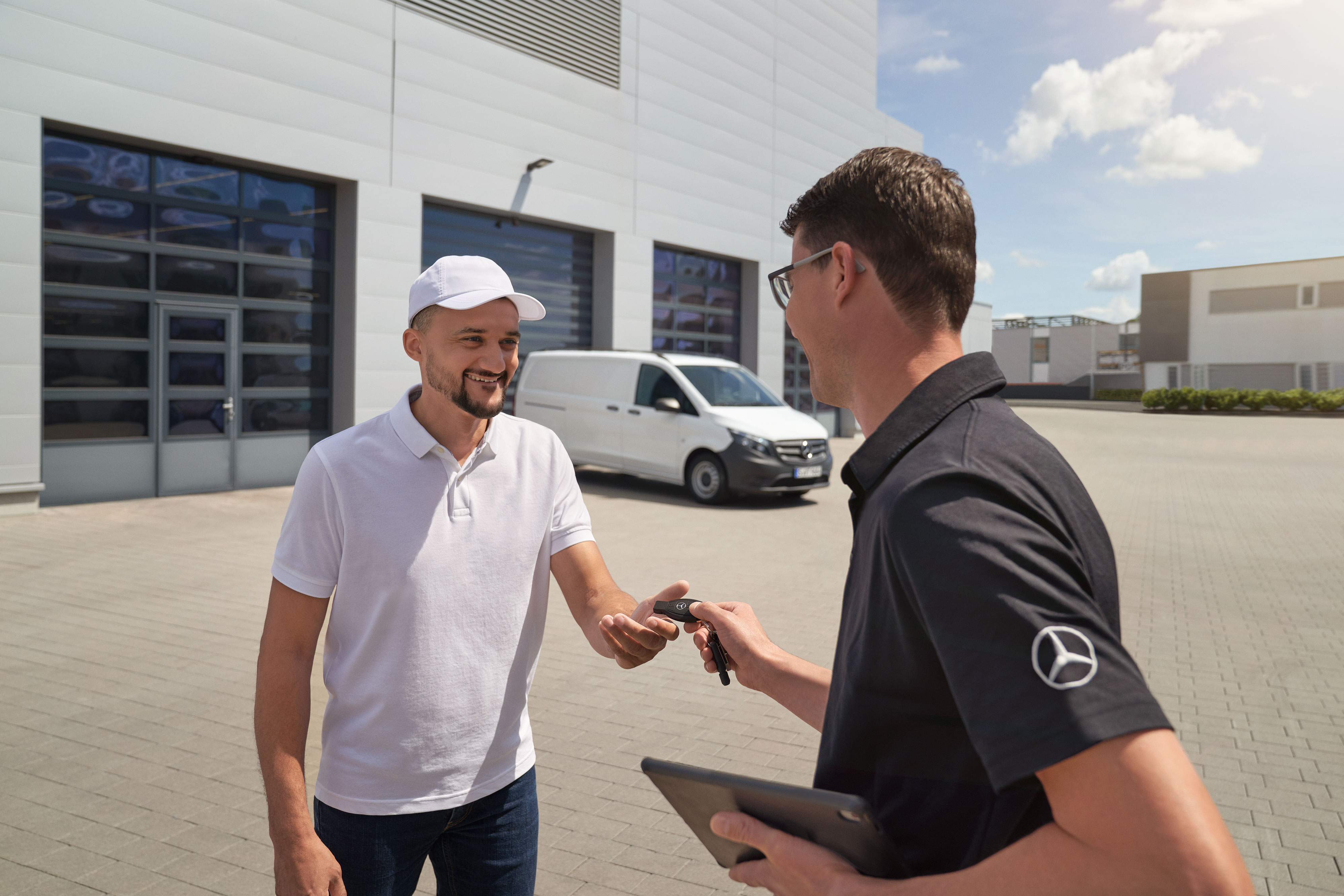 Mercedes-Benz | Van ServiceCare | Opțiuni suplimentare Un tehnician înmânează telecomanda unui client cu o furgonetă Mercedes-Benz Vito albă în fundal.