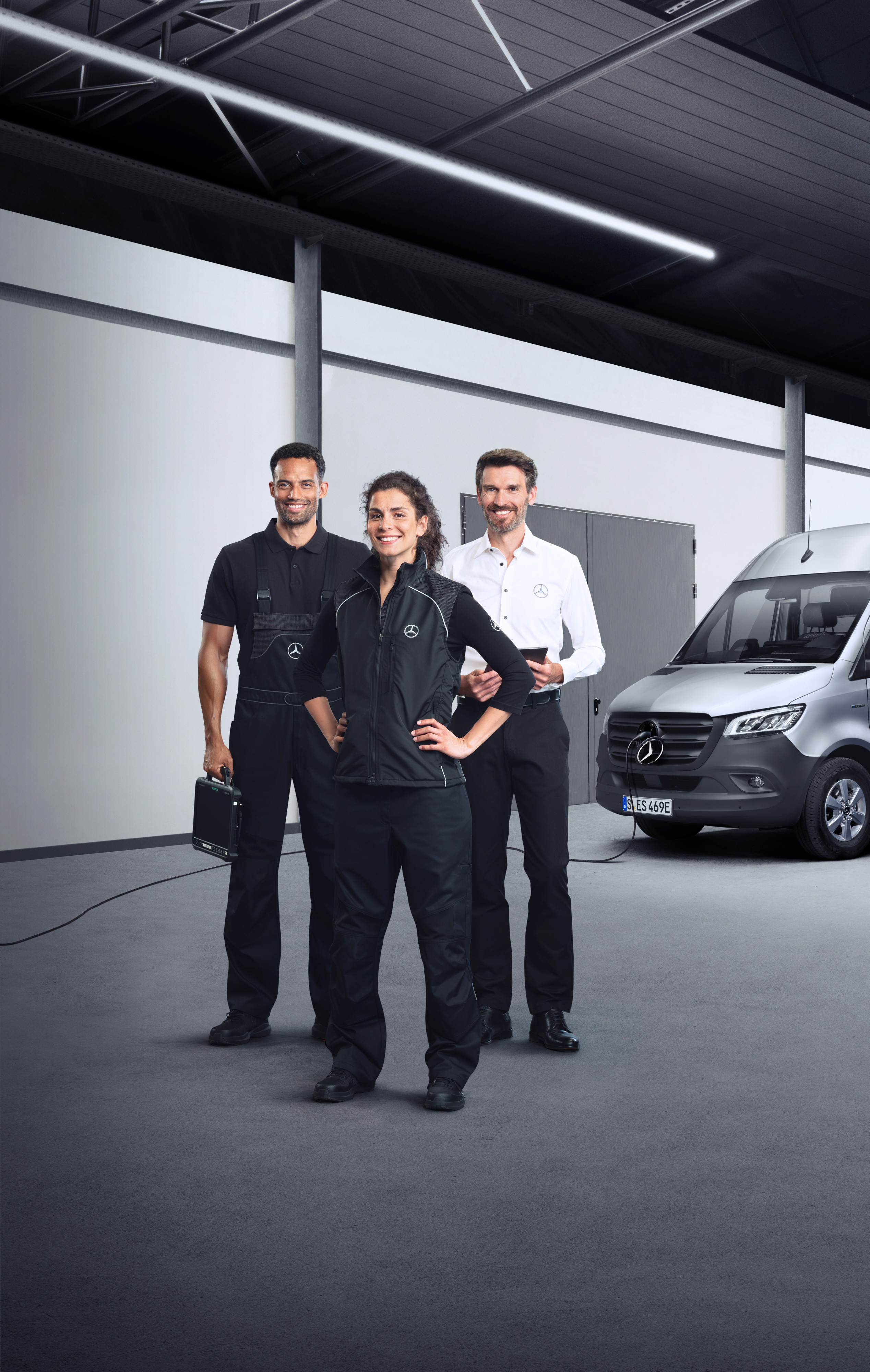 Mercedes-Benz | Servicii autovehicule electrice Trei angajați în fața unui Mercedes-Benz eSprinter, cu cablu de încărcare conectat.