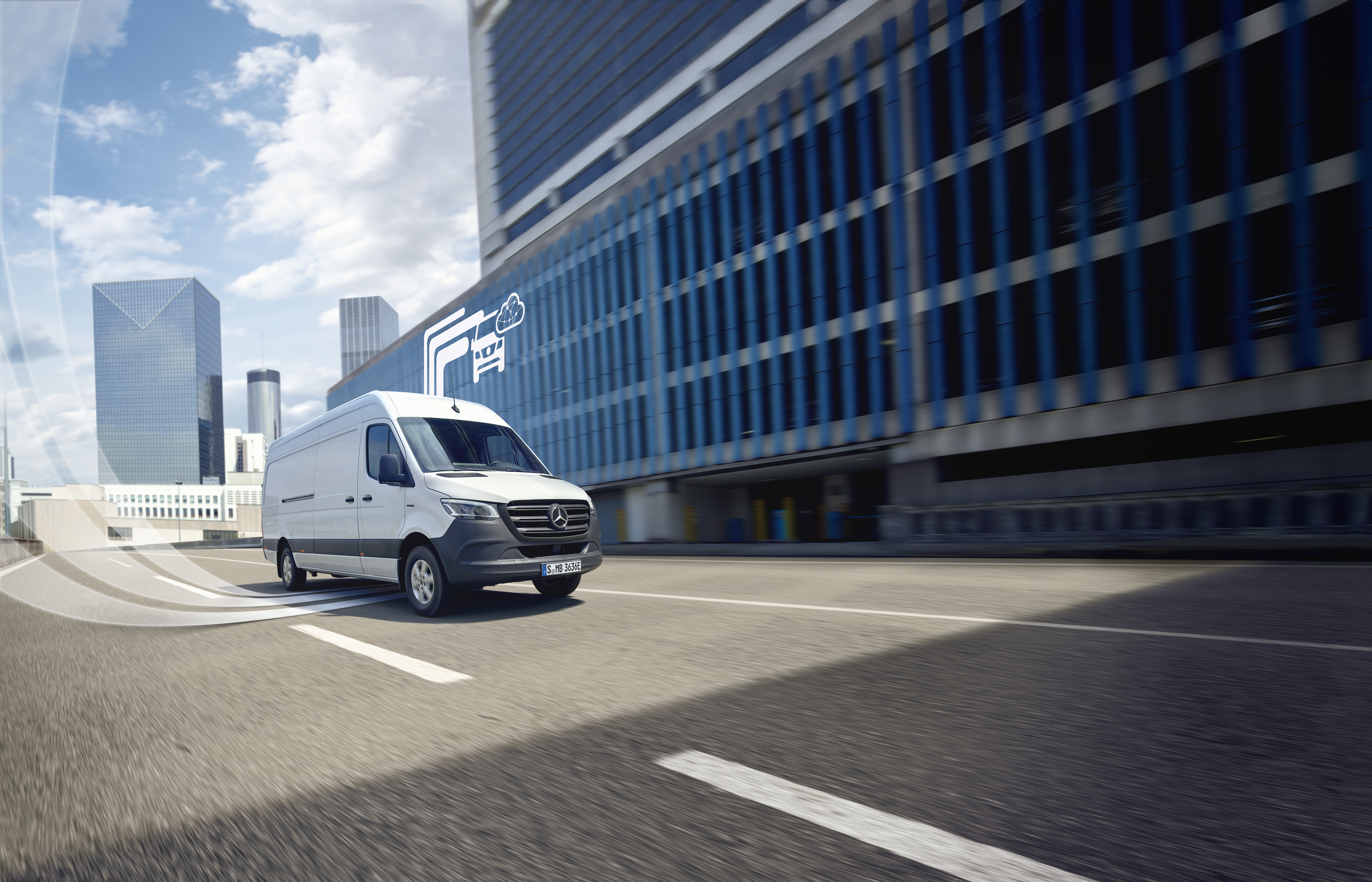 Mercedes-Benz | Tehnologie autovehicule comerciale | Extraopțiuni digitale Autovehicul comercial Mercedes-Benz alb deplasându-se prin oraș, simbol digital al tehnologiei Mercedes-Benz în fundal.