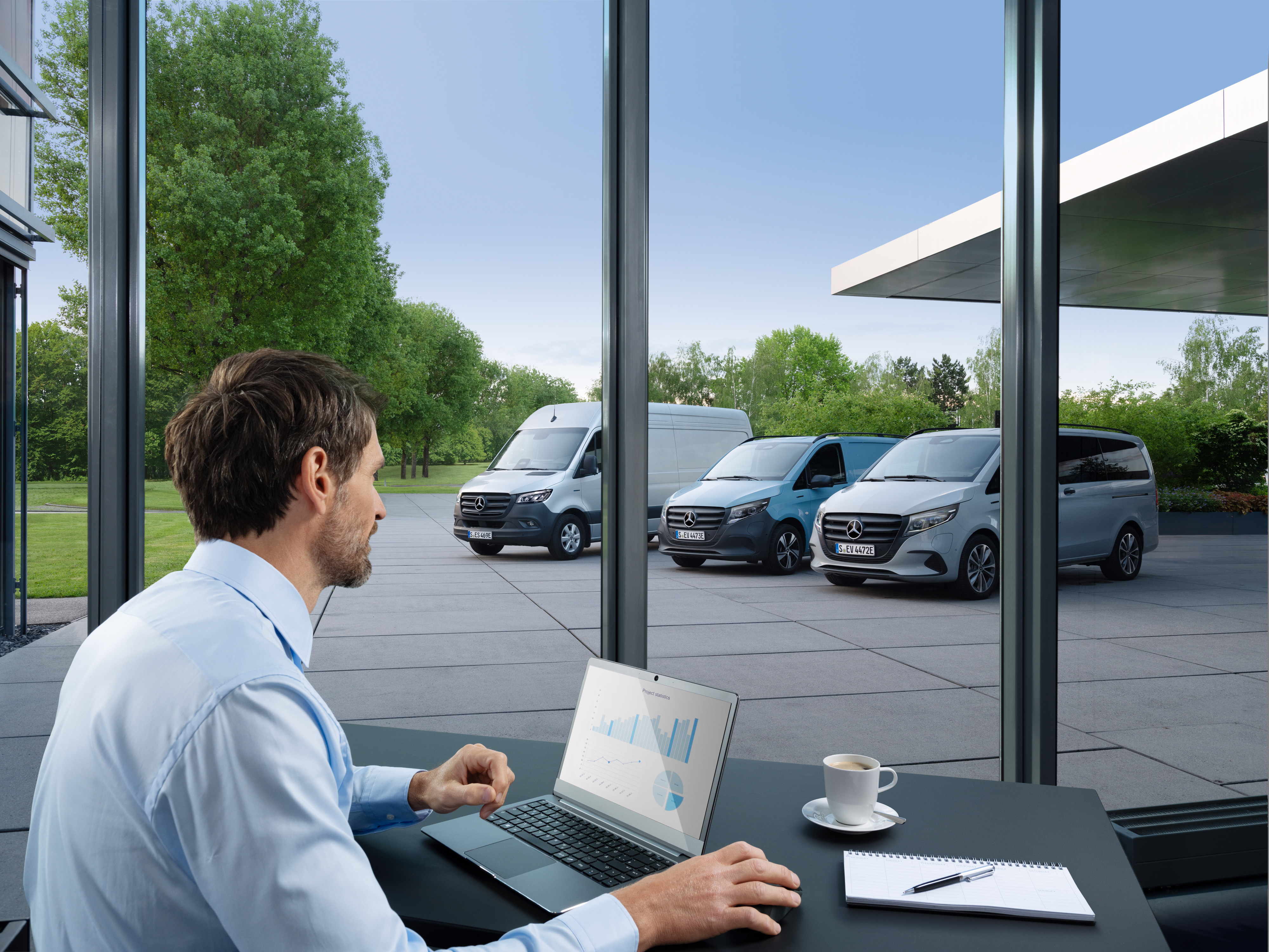 Mercedes-Benz | Tehnologie autovehicule comerciale | Van Uptime Monitor Un bărbat monitorizează cu ajutorul unui laptop mai multe autovehicule comerciale Mercedes-Benz parcate, simbolizând managementul digital al flotelor.