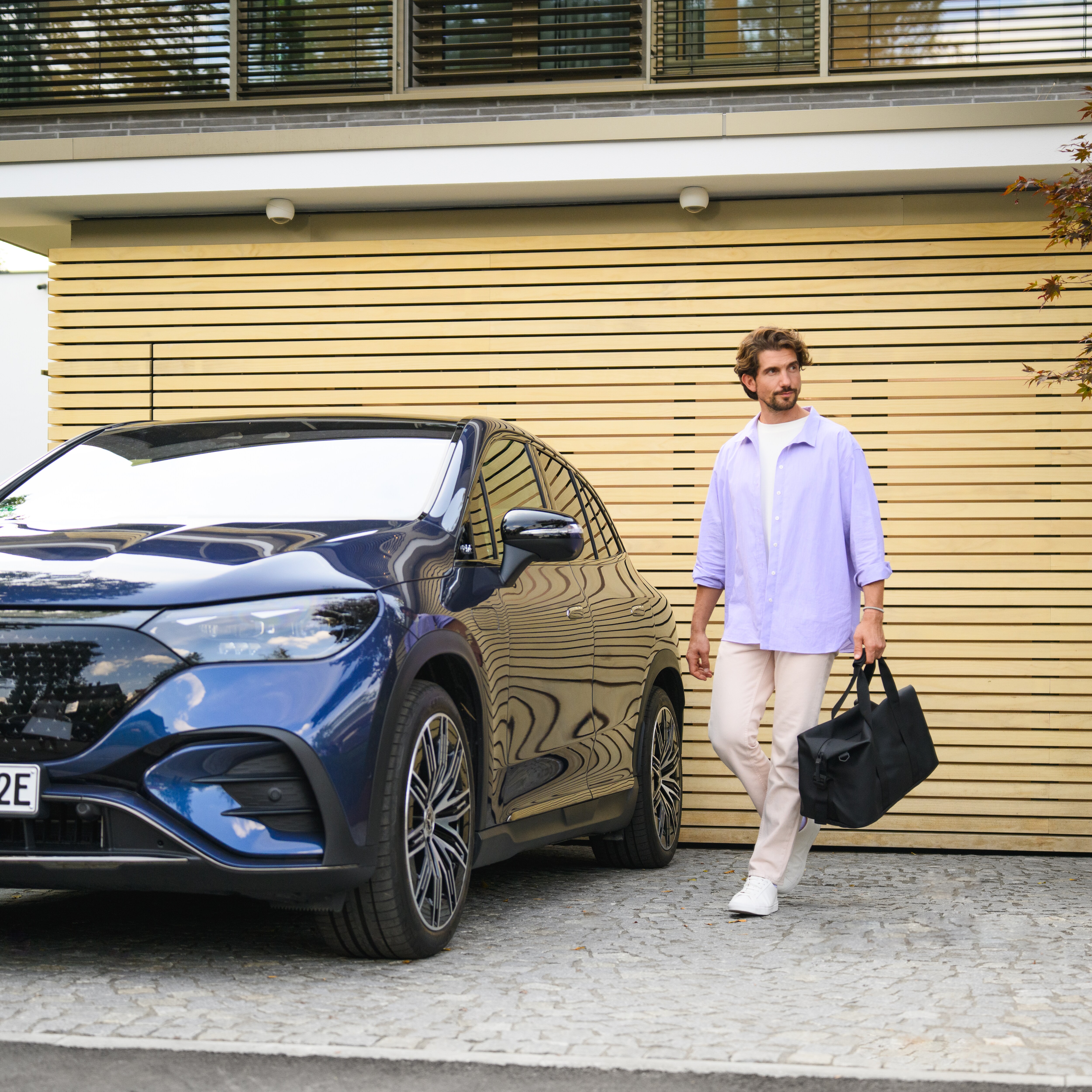 Un bărbat și o femeie se apropie de un Mercedes-Benz EQS alb