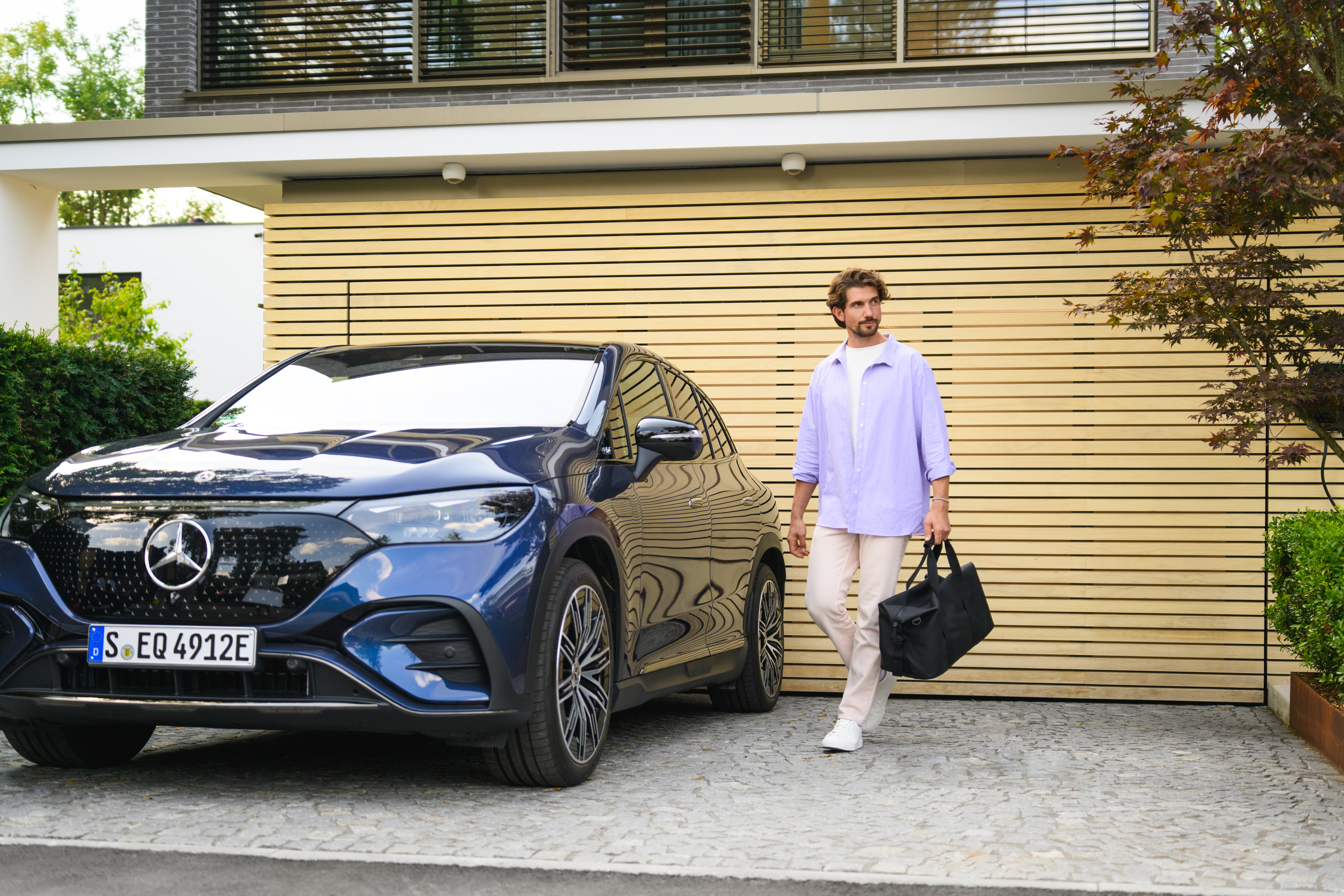 Oferte | Servicii financiare | Mercedes-Benz Financial Services Un bărbat și o femeie se apropie de un Mercedes-Benz EQS alb