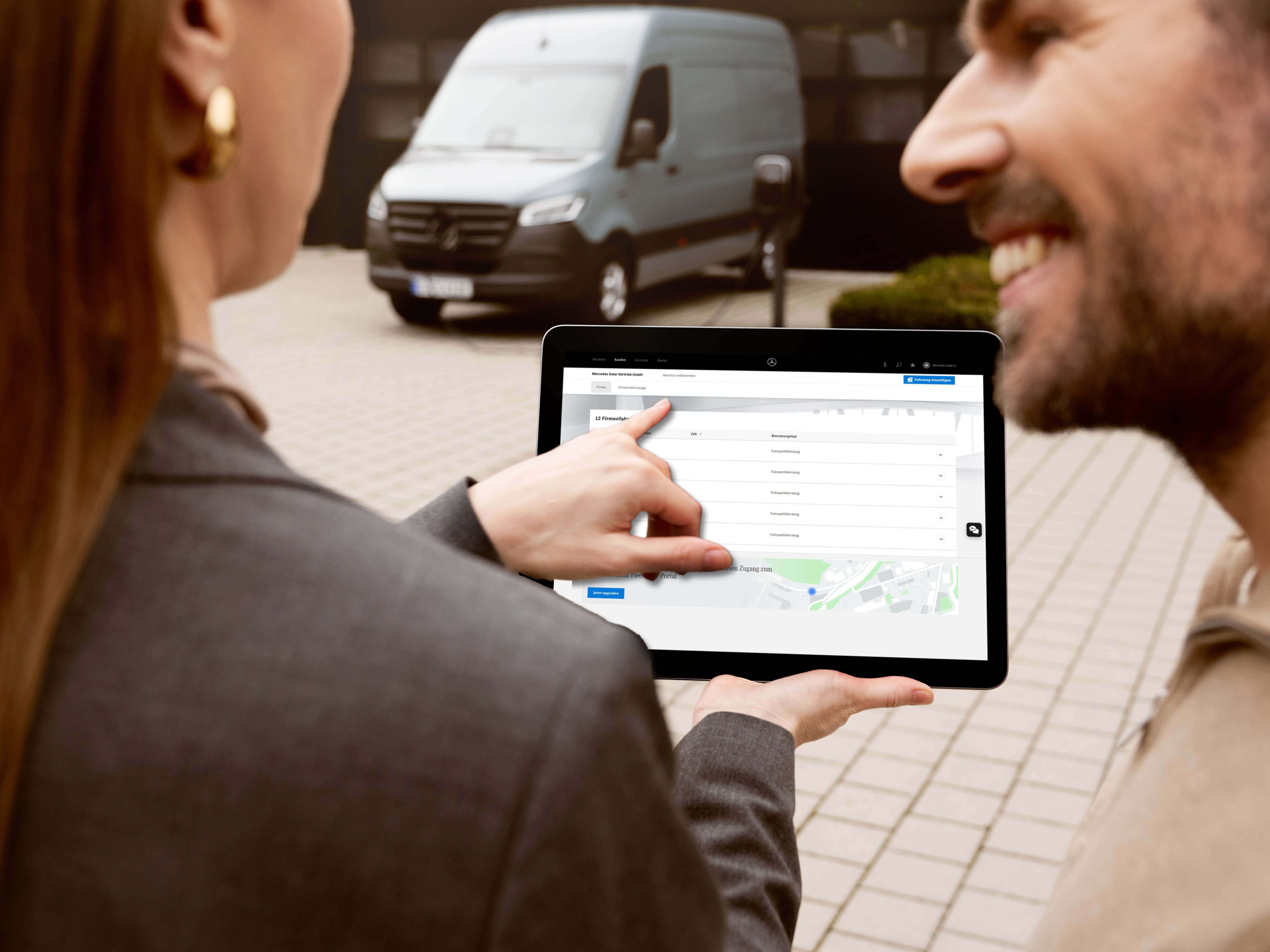 Woman holding tablet overlooking white Mercedes-Benz