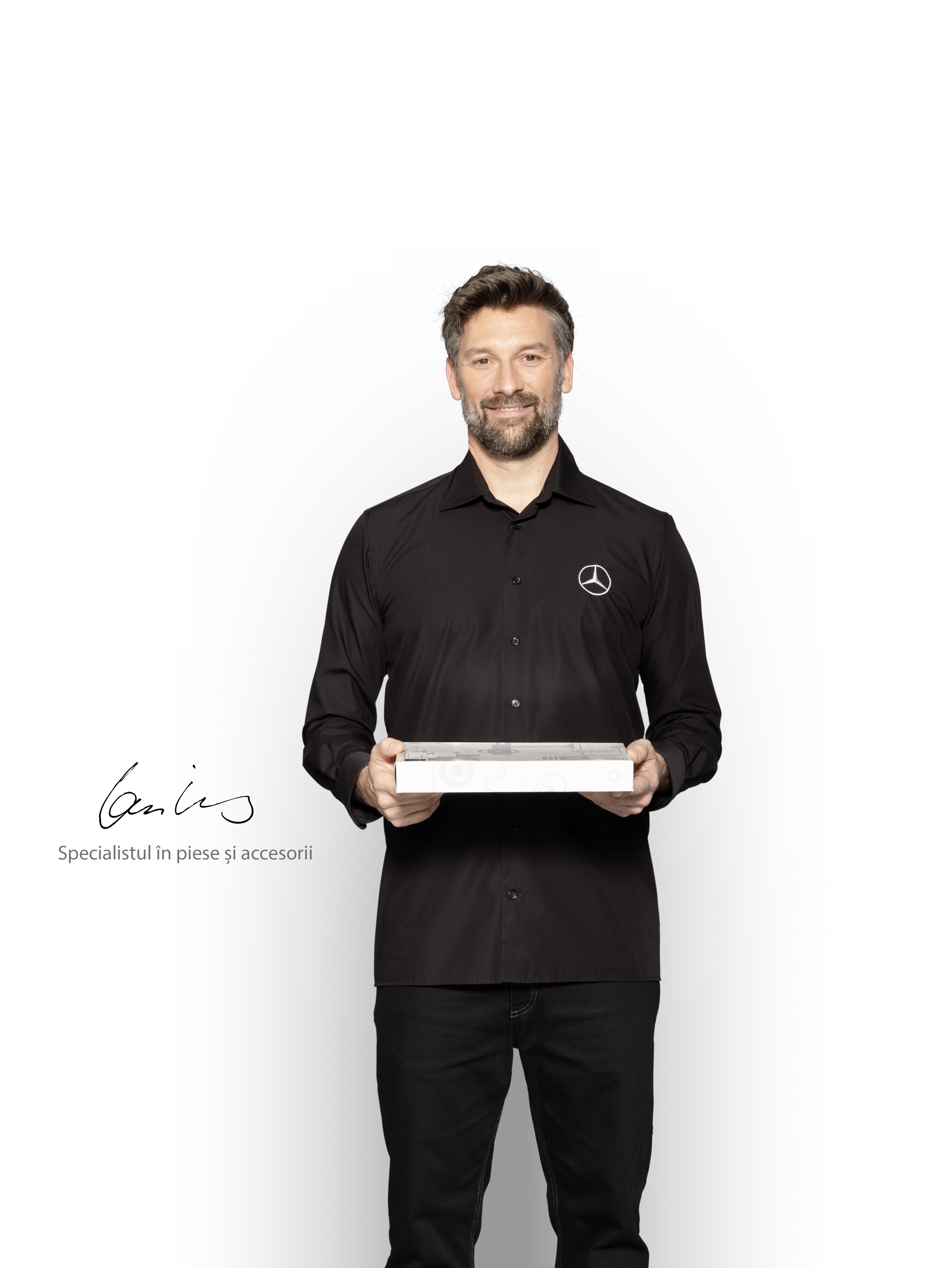 Tehnician Mercedes-Benz cu o cutie în mână pentru a arăta piese de origine Mercedes-Benz.