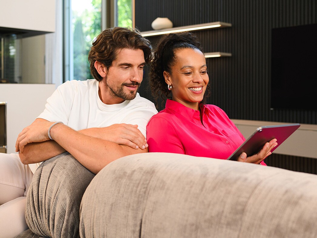 Un bărbat și o femeie stau la masă și se uită împreună la un laptop